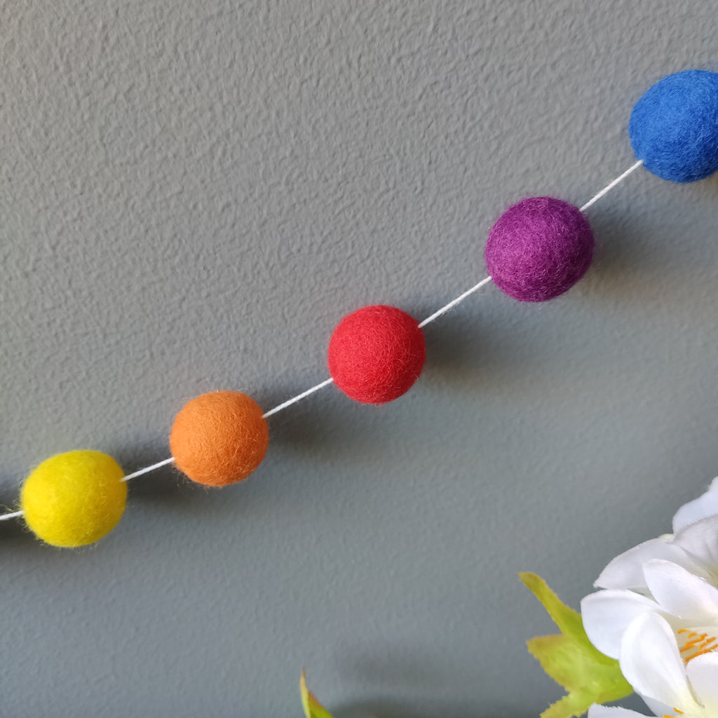 Zoom sur les boules de feutre de la guirlande de pompons aux couleurs arc-en-ciel vives