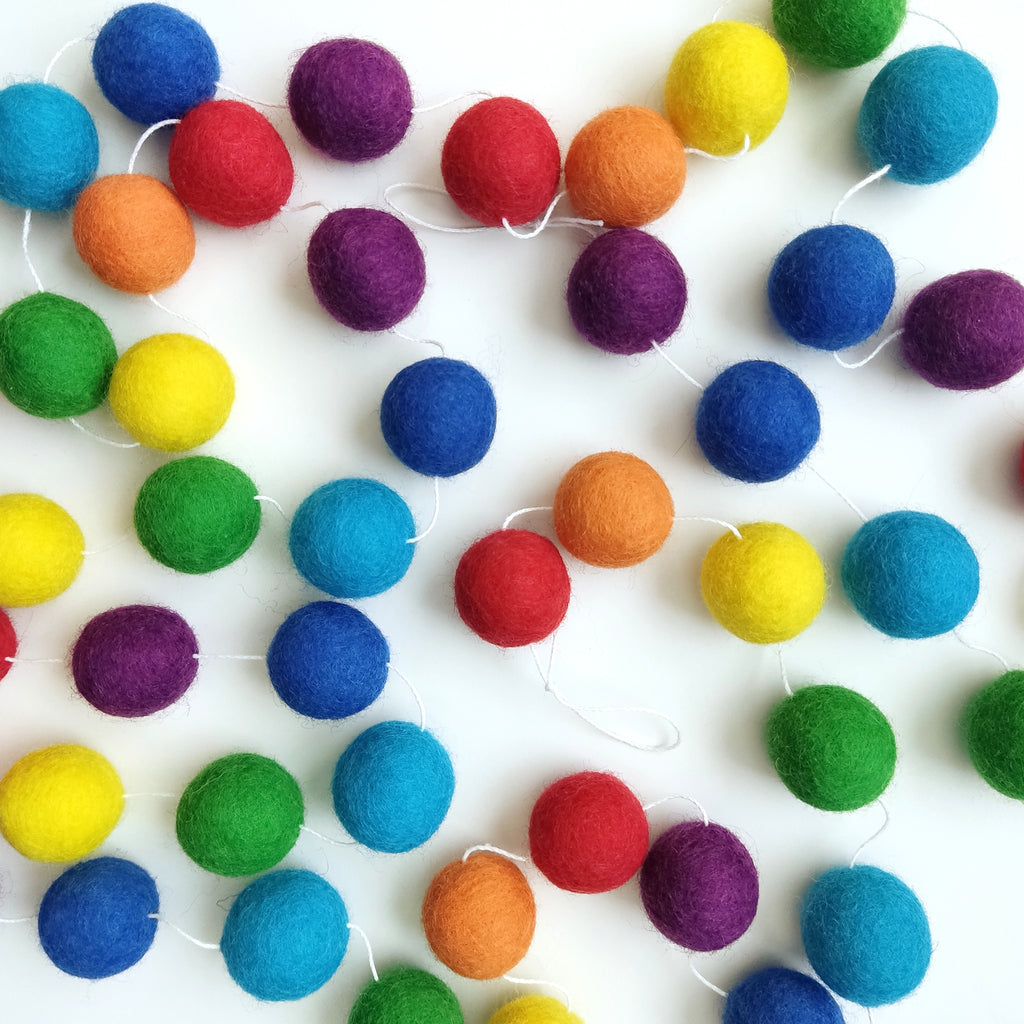 Guirlande de boules de feutre arc-en-ciel classique vue de dessus sur une table montrant toutes les couleurs