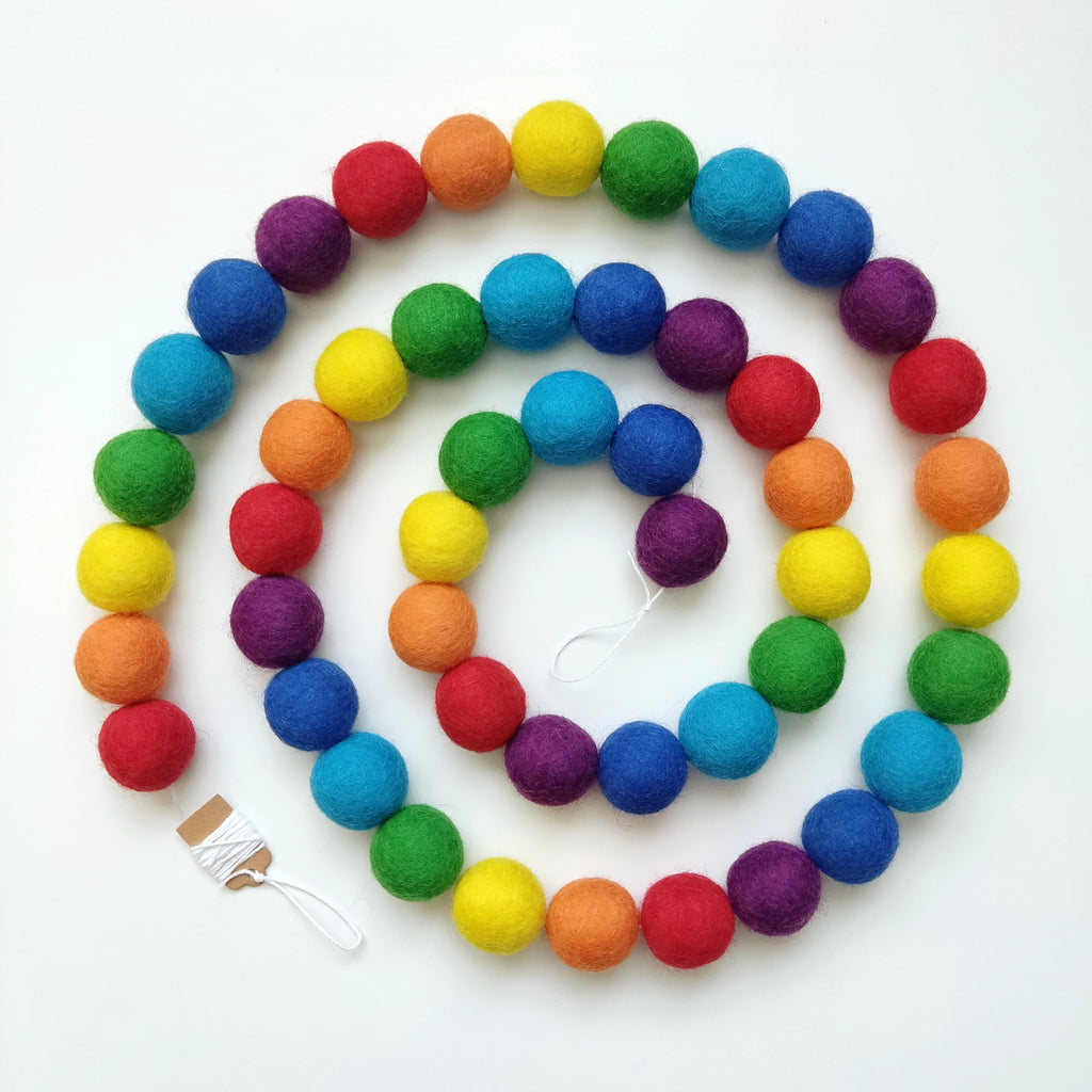 Guirlande de boules de feutre arc-en-ciel avec les pompons non-espacés sur le fil et disposée en spirale vue de dessus