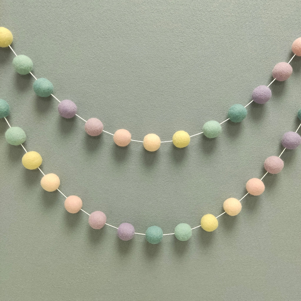 Guirlande de pompons feutrés aux couleurs arc-en-ciel pastel estompées pour décoration murale