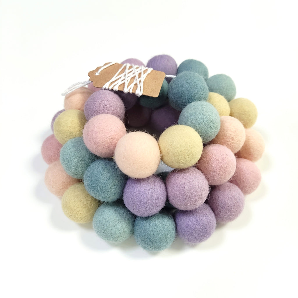Guirlande de pompons de feutre aux couleurs pastel enroulée avec les pompons rassemblés sur le fil