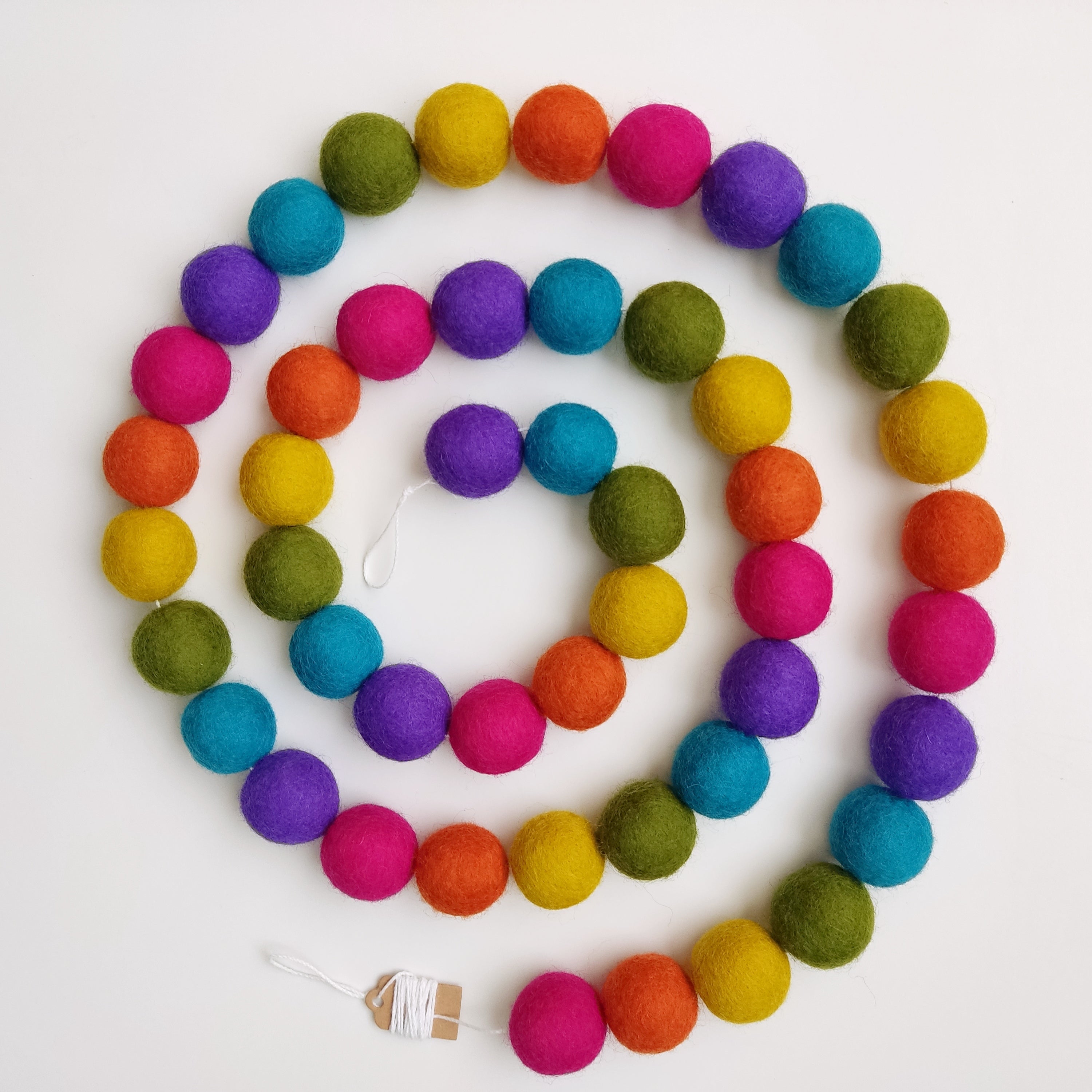 Guirlande de pompons feutrés arc-en-ciel mexicain disposée en spirale vue de dessus