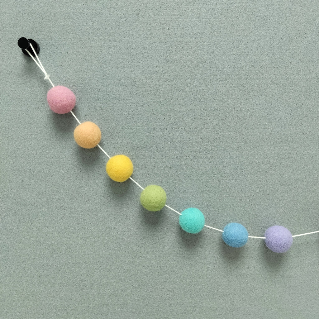 Zoom sur les couleurs de la guirlande arc-en-ciel pastel : rose cerisier, orange pêche, jaune maïs, vert wasabi, bleu lagon, bleu ciel et lavande