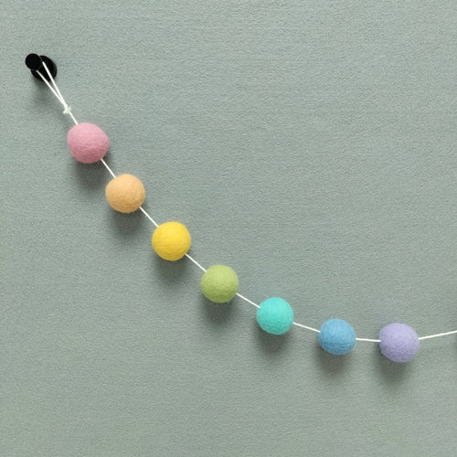 Zoom sur les couleurs de la guirlande arc-en-ciel pastel : rose cerisier, orange pêche, jaune maïs, vert wasabi, bleu lagon, bleu ciel et lavande