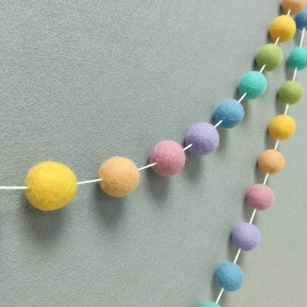 Vue de profil de la guirlande en boules de feutre arc-en-ciel pastel