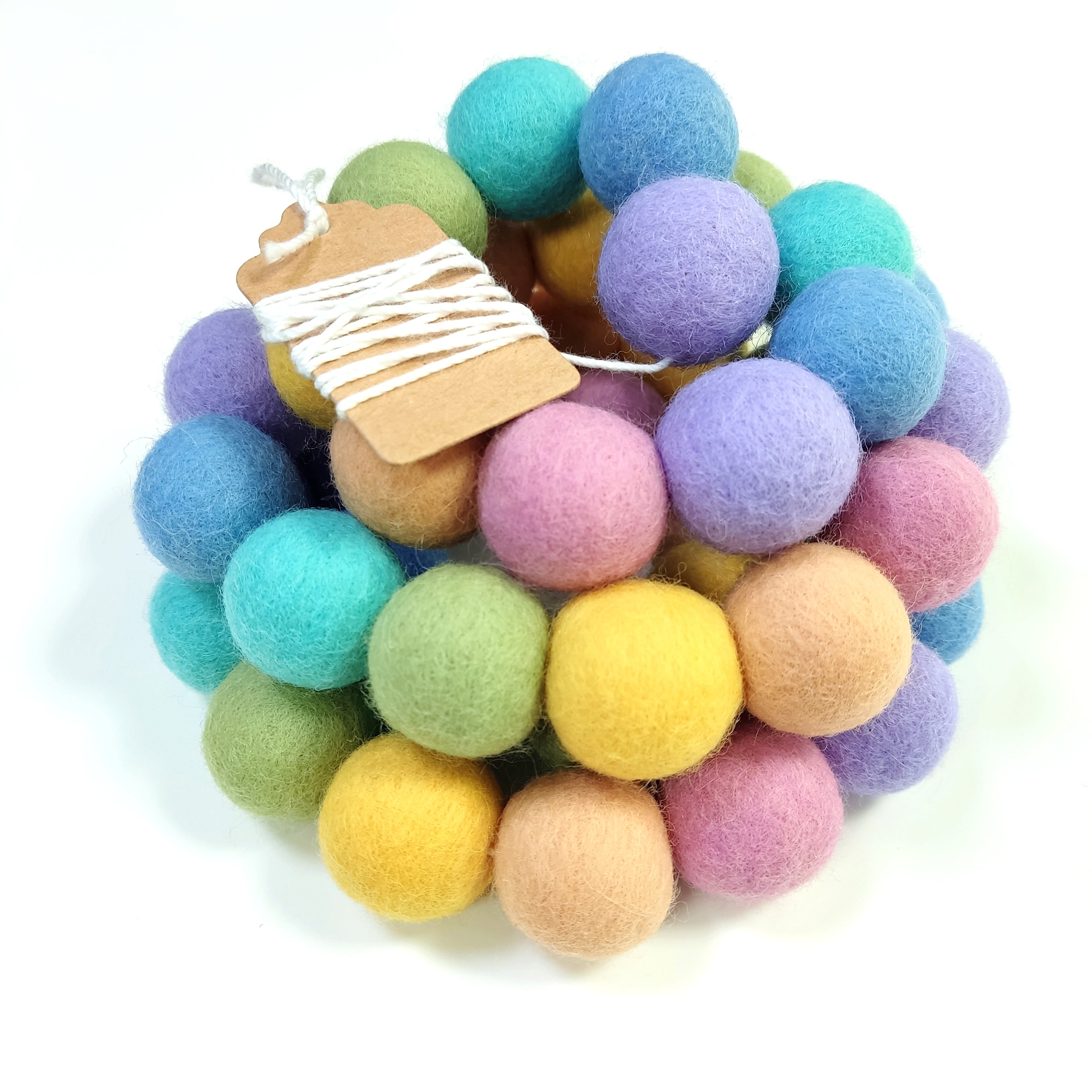 Guirlande en boules de feutre arc-en-ciel pastel enroulée sur elle-même avec étiquette