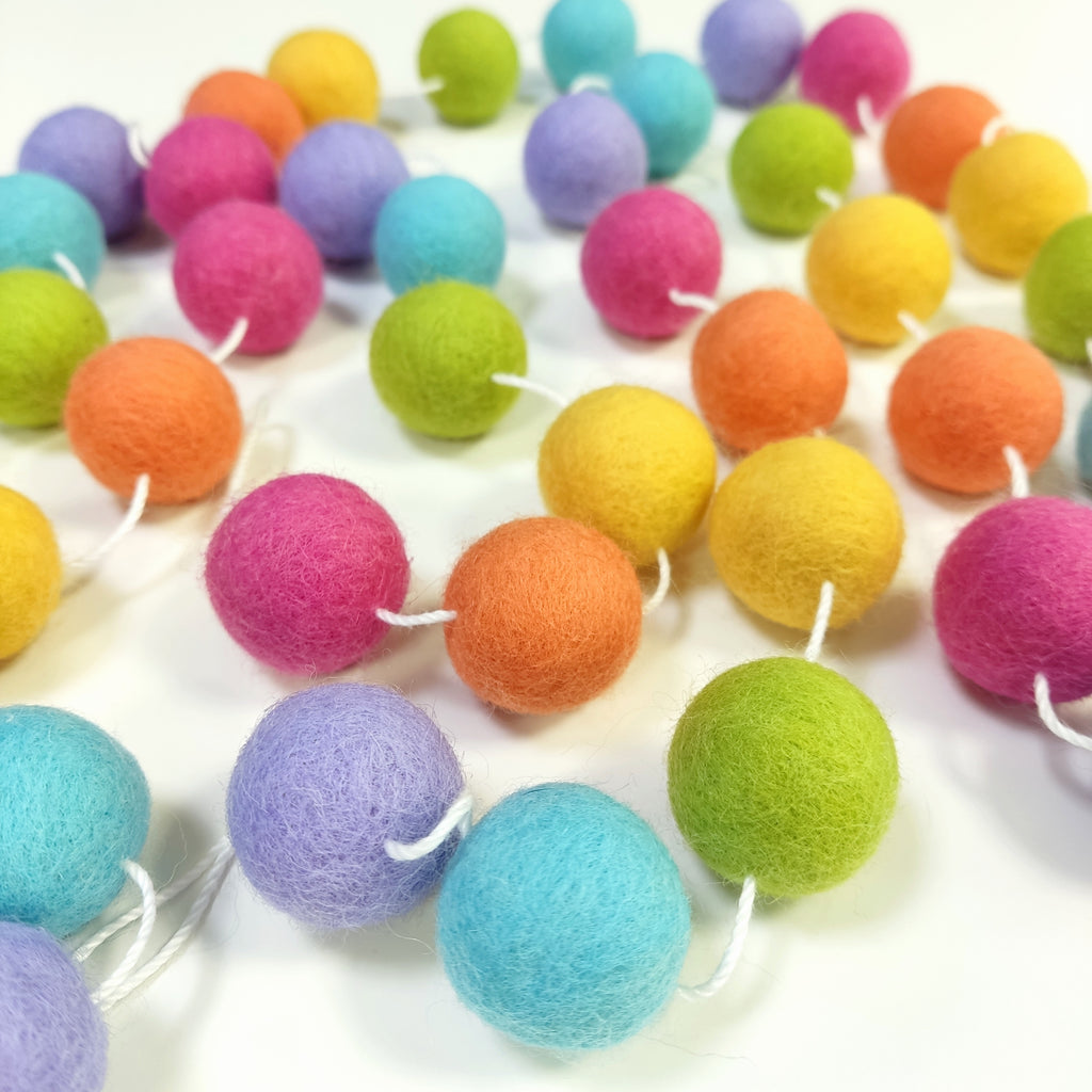 Guirlande de boules de laine feutrée étalée sur une table