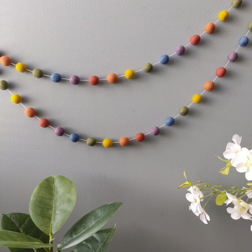 Guirlande aux couleurs arc-en-ciel vintage faite main accrochée sur un mur