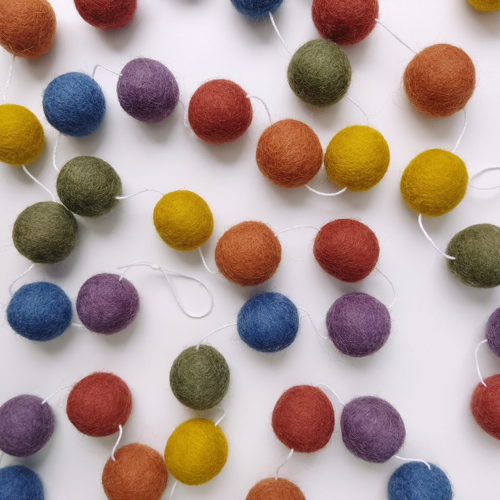 Guirlande arc-en-ciel vintage avec les pompons disposés sur une table vue de dessus
