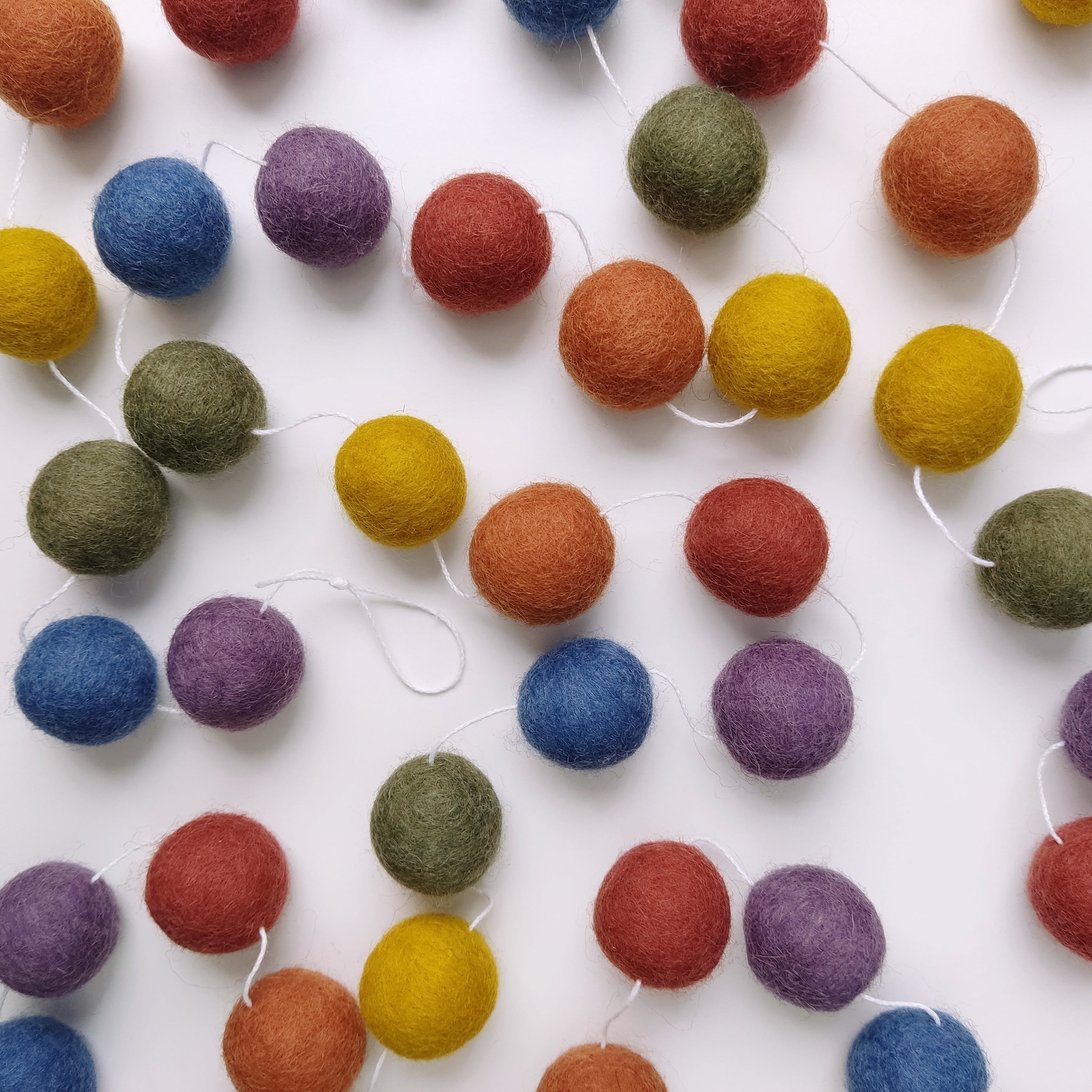 Guirlande arc-en-ciel vintage avec les pompons disposés sur une table vue de dessus
