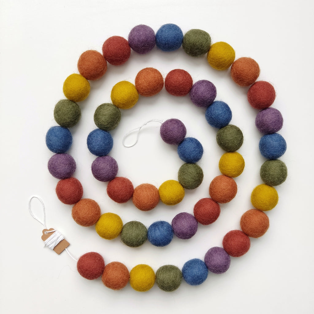 Guirlande arc-en-ciel vintage avec les pompons rassemblés sur le fil et disposée en spirale sur une table