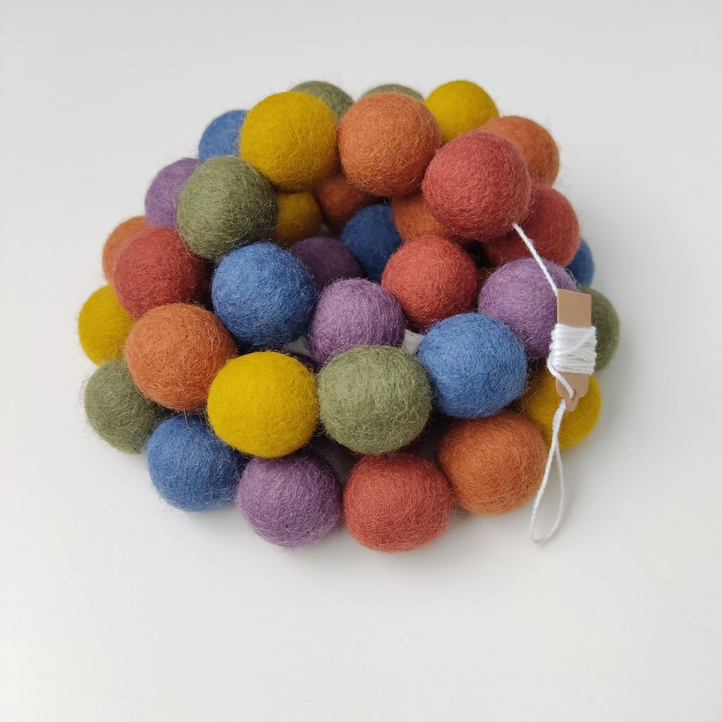 Guirlande de pompons arc-en-ciel vintage enroulée sur elle-même vue de près