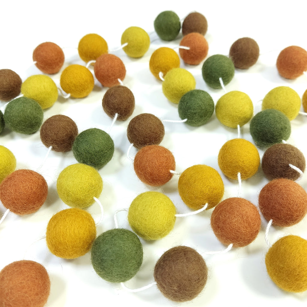Guirlande de pompons automne en boule de feutre étalée sur une table
