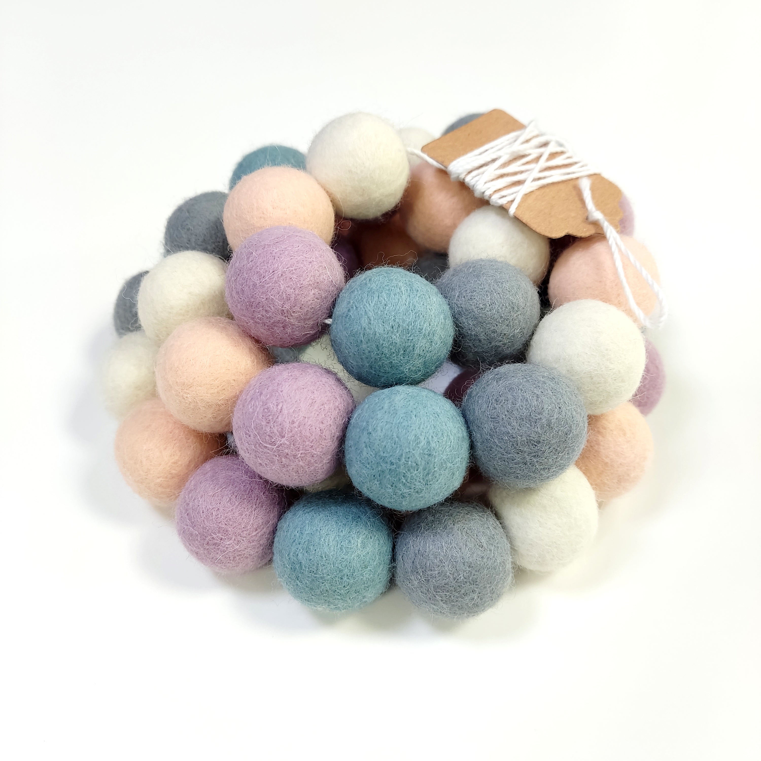 Détail de la guirlande de pompons feutrés brume nordique bleu gris blanc lilas beige rosé avec étiquette