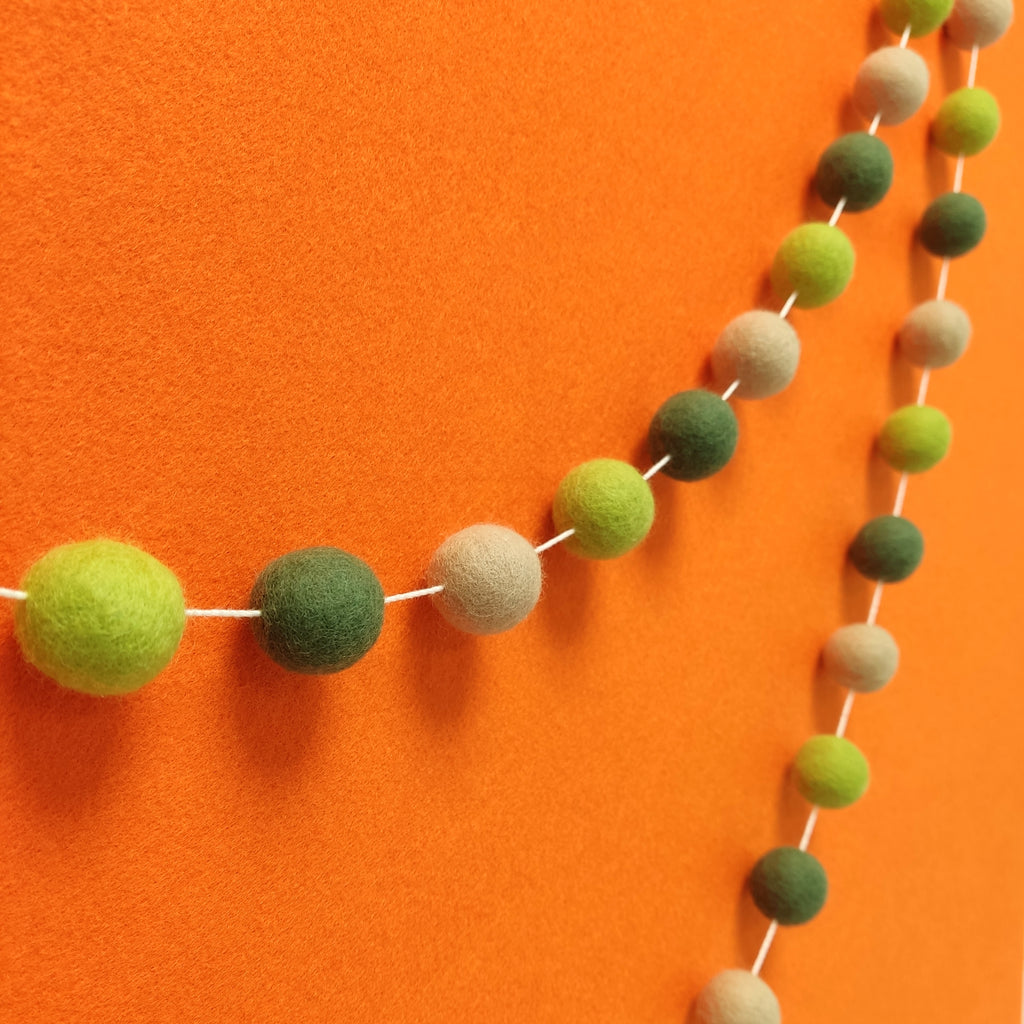 Guirlande de pompons pour chambre d'enfant tons verts et beige vue de près