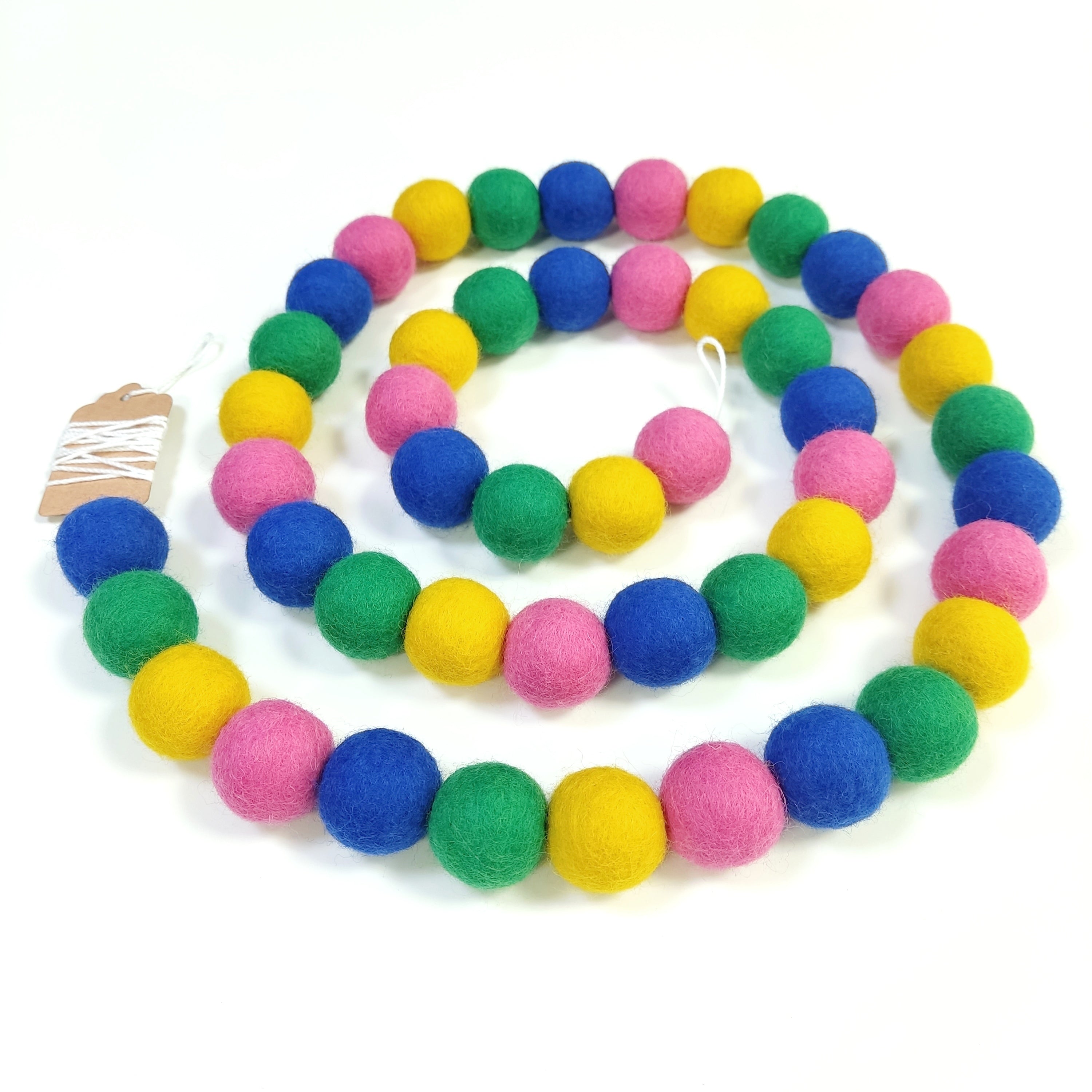 Guirlande en boules de feutre confettis disposée en spirale sur une table