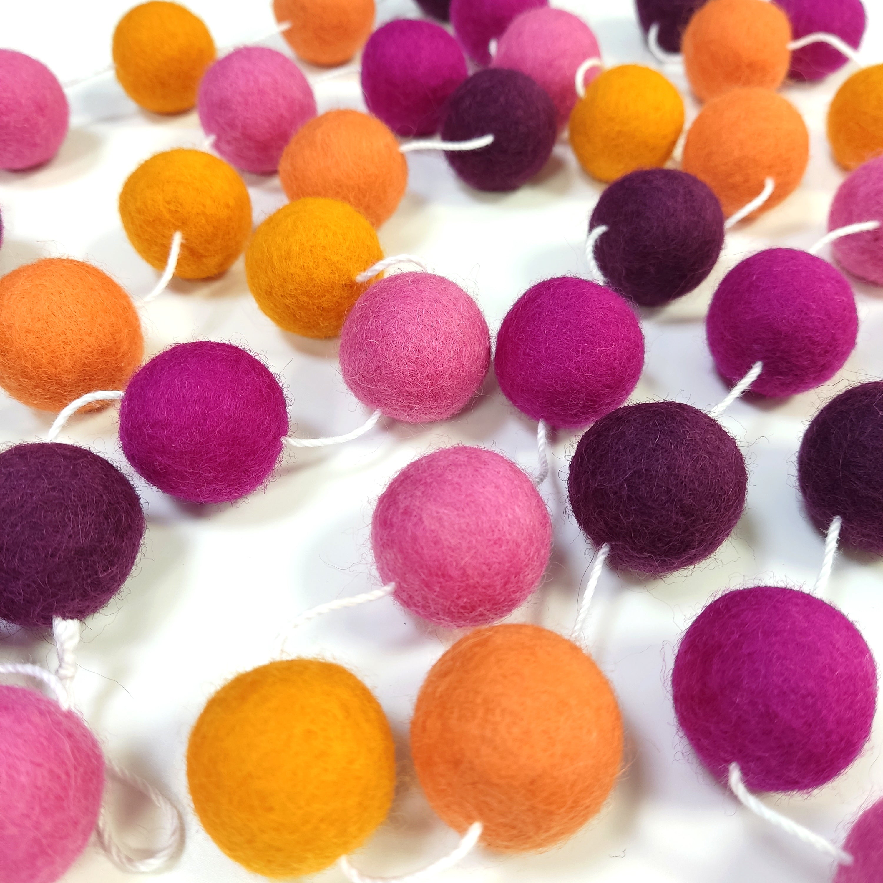 Guirlande de pompons dahlias aux teintes rose et orange étalée sur une table