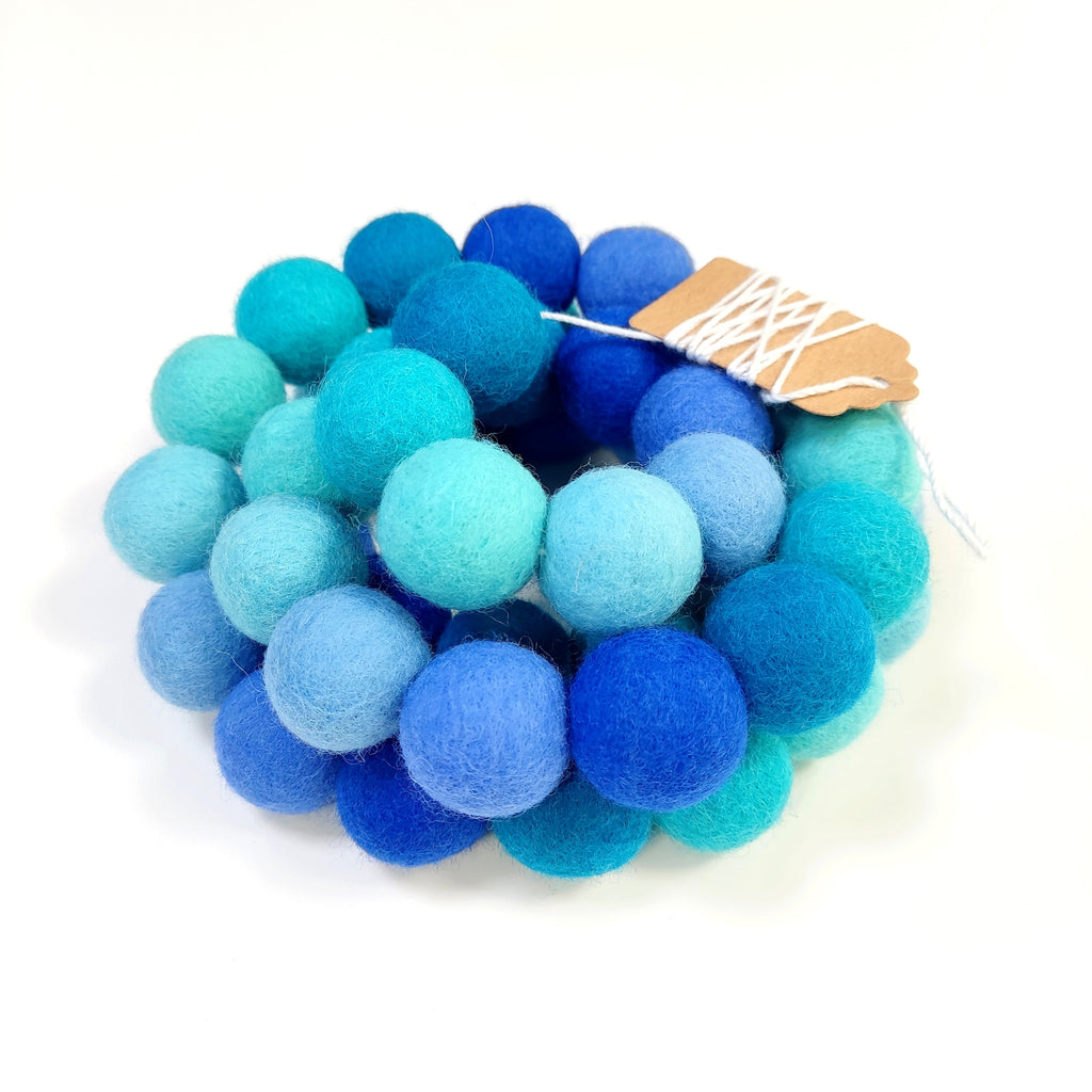 Détail de la guirlande de pompons feutrés dégradé bleu avec étiquette