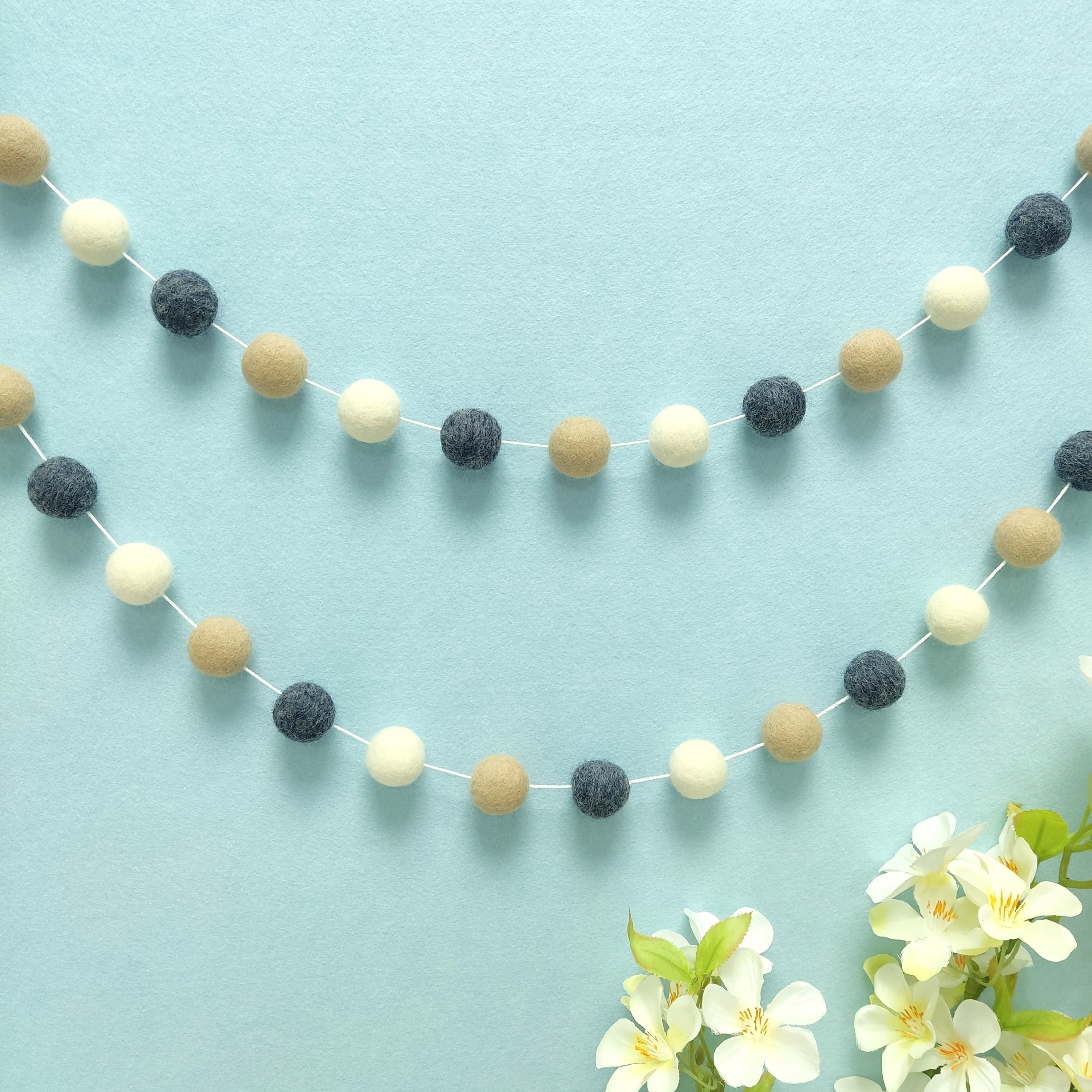 Guirlande de pompons denim beige fixée en décoration murale