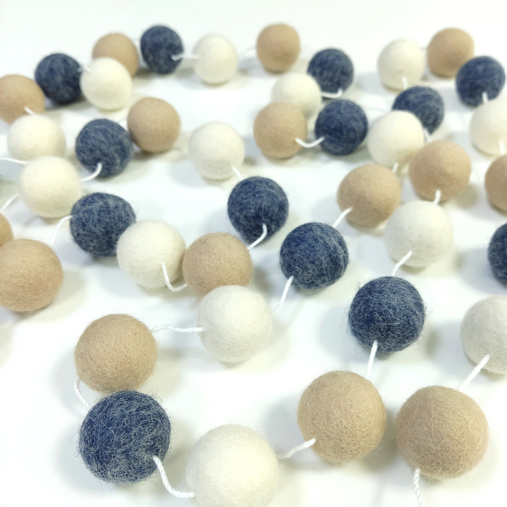 Guirlande de pompons en feutre de laine mérinos étalée sur une table
