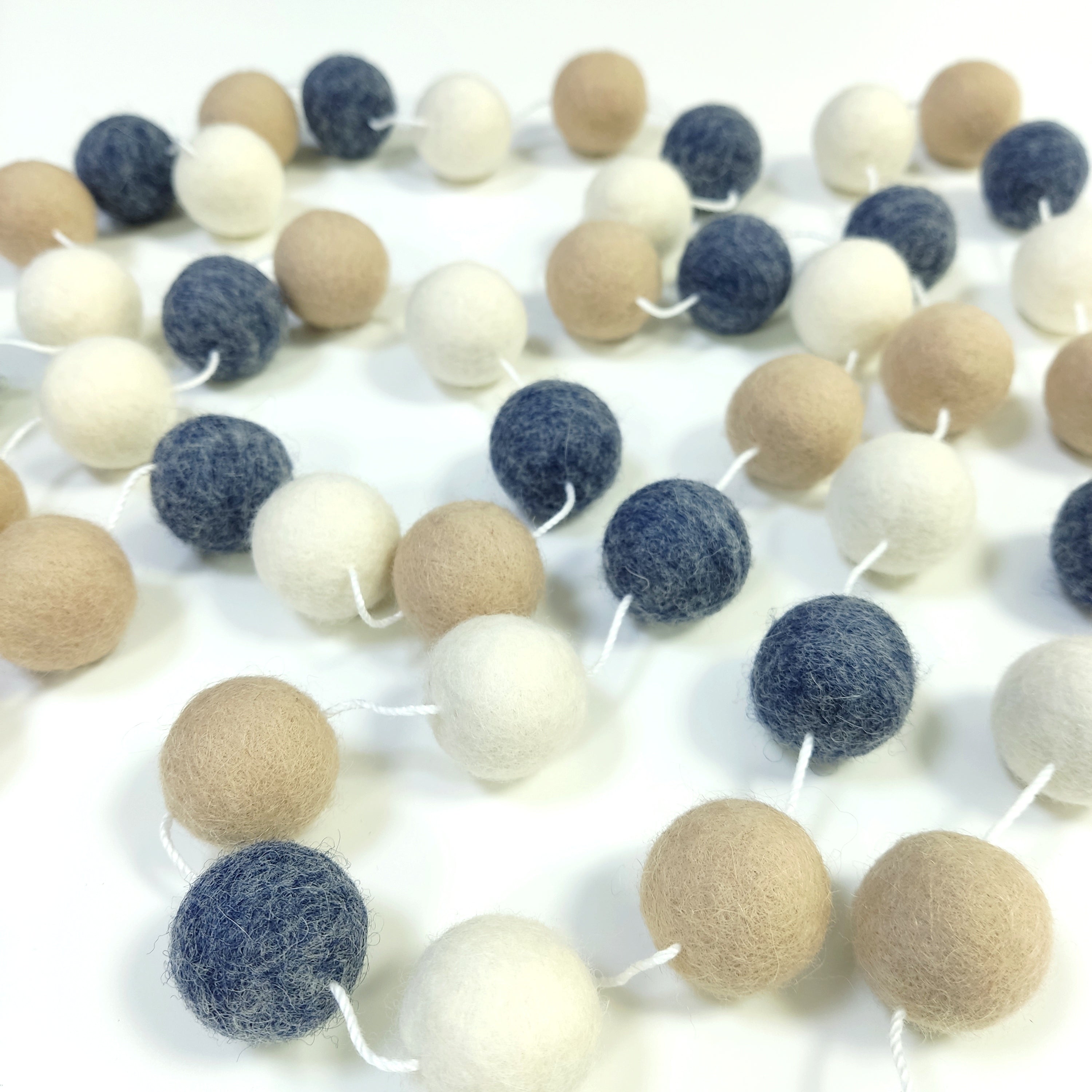Guirlande de pompons en feutre de laine mérinos étalée sur une table