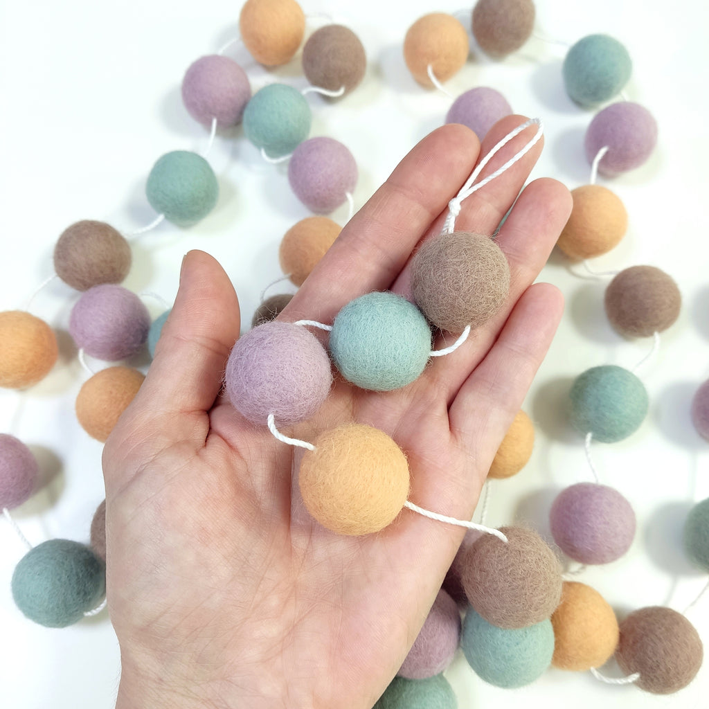 Détail des pompons de 2,5 cm de la guirlande dolce vita dans une main