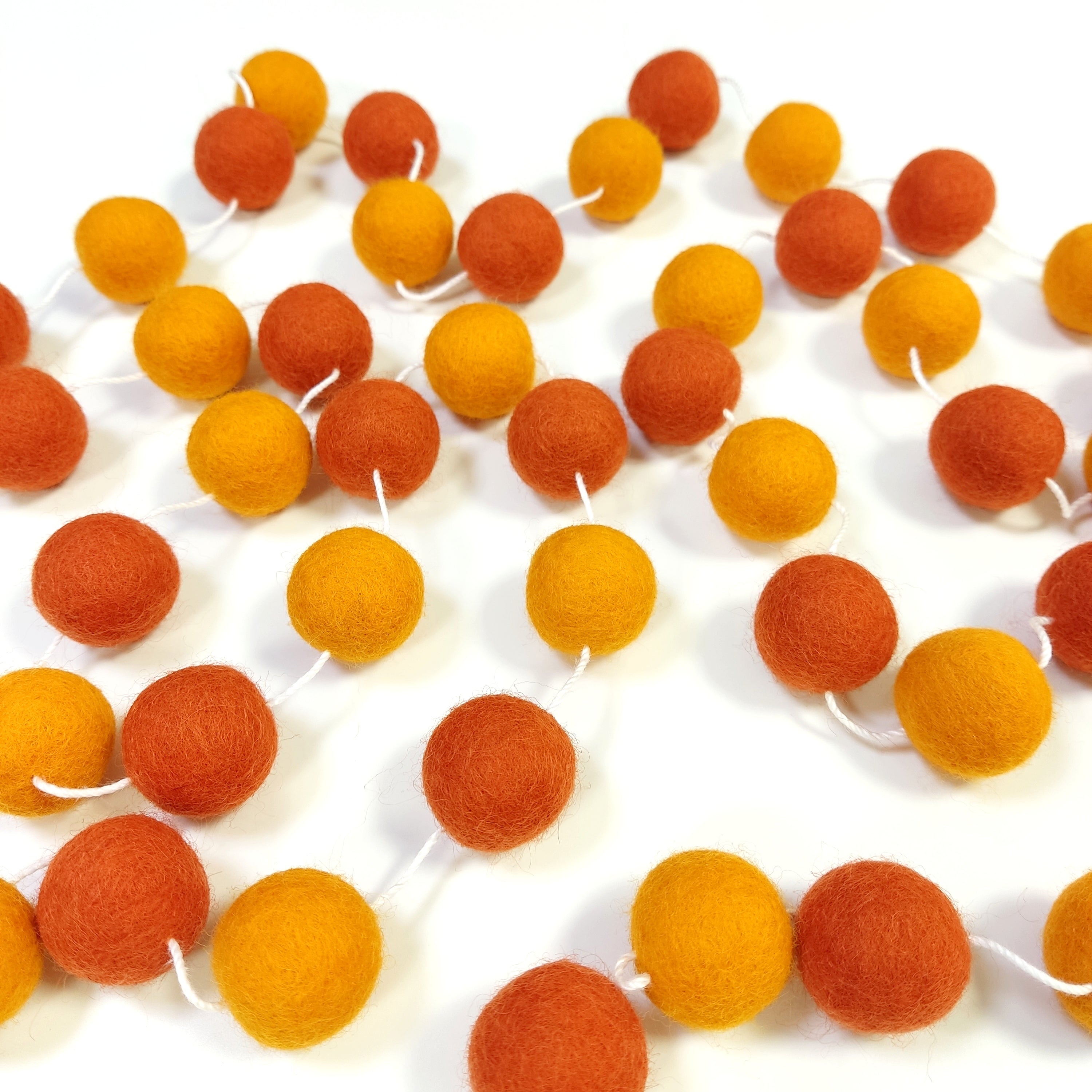Guirlande de pompons de feutre orange étalée sur une table