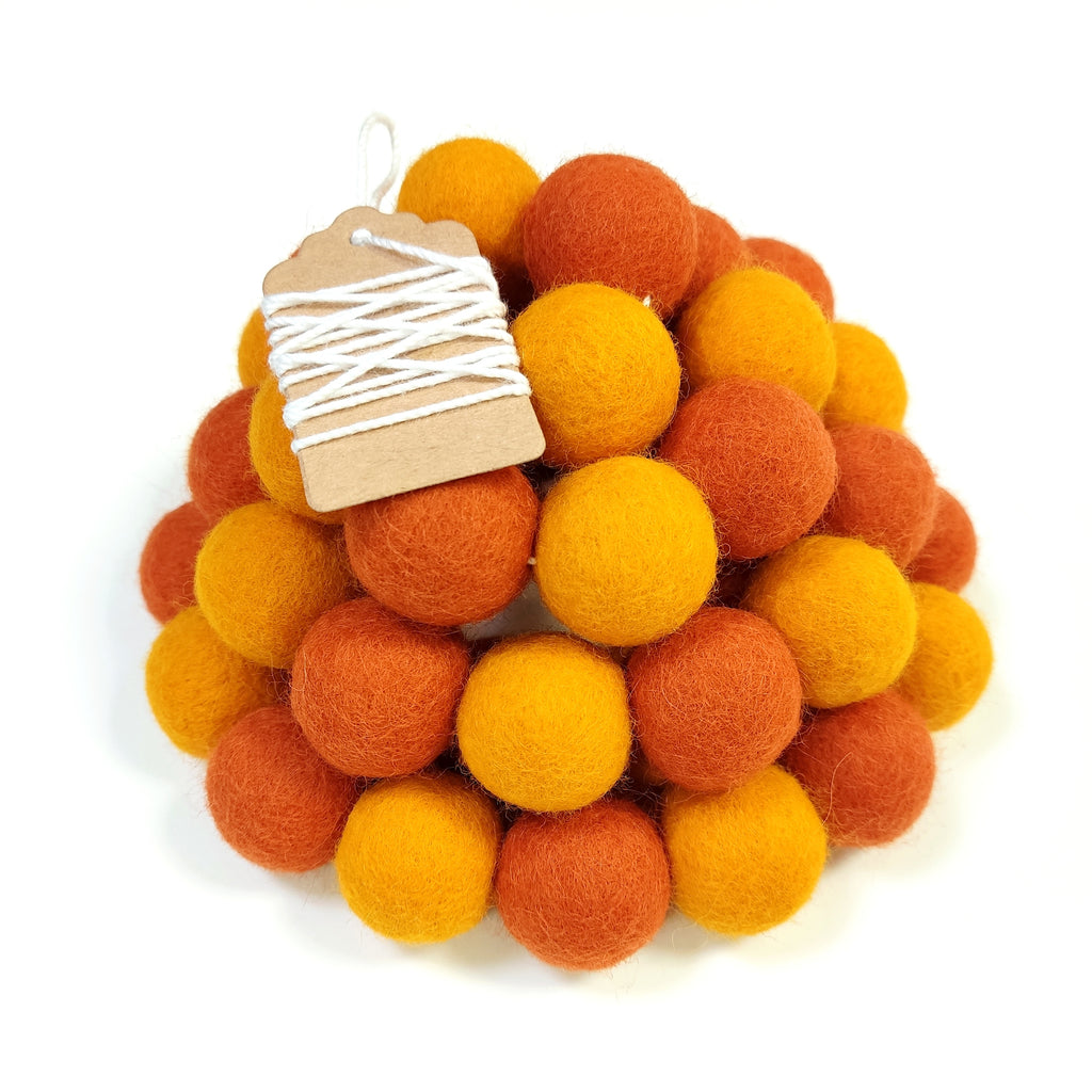 Zoom sur la guirlande duo orange en pompons feutrés avec étiquette
