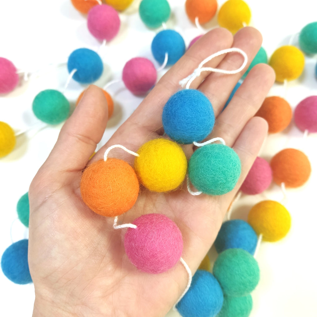 Détail des pompons de feutre de la guirlande flashy dans une main