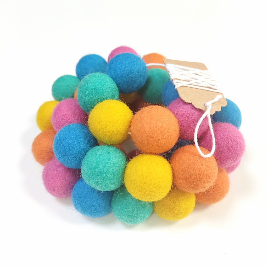 Zoom sur la guirlande flashy avec les pompons rassemblés sur le fil et l'étiquette