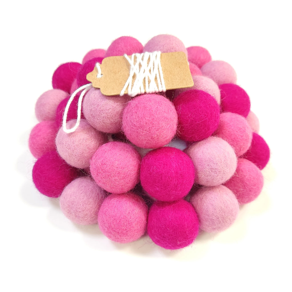 Zoom sur la guirlande de pompons feutrés aux tons roses avec son étiquette