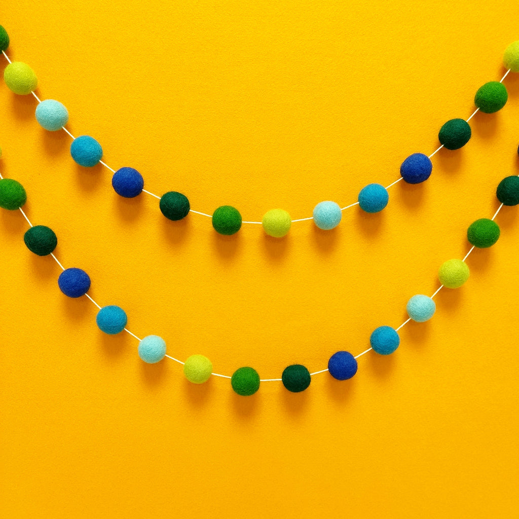 Guirlande boules de feutre bleu et vert tropicale fixée au mur en arc de cercle