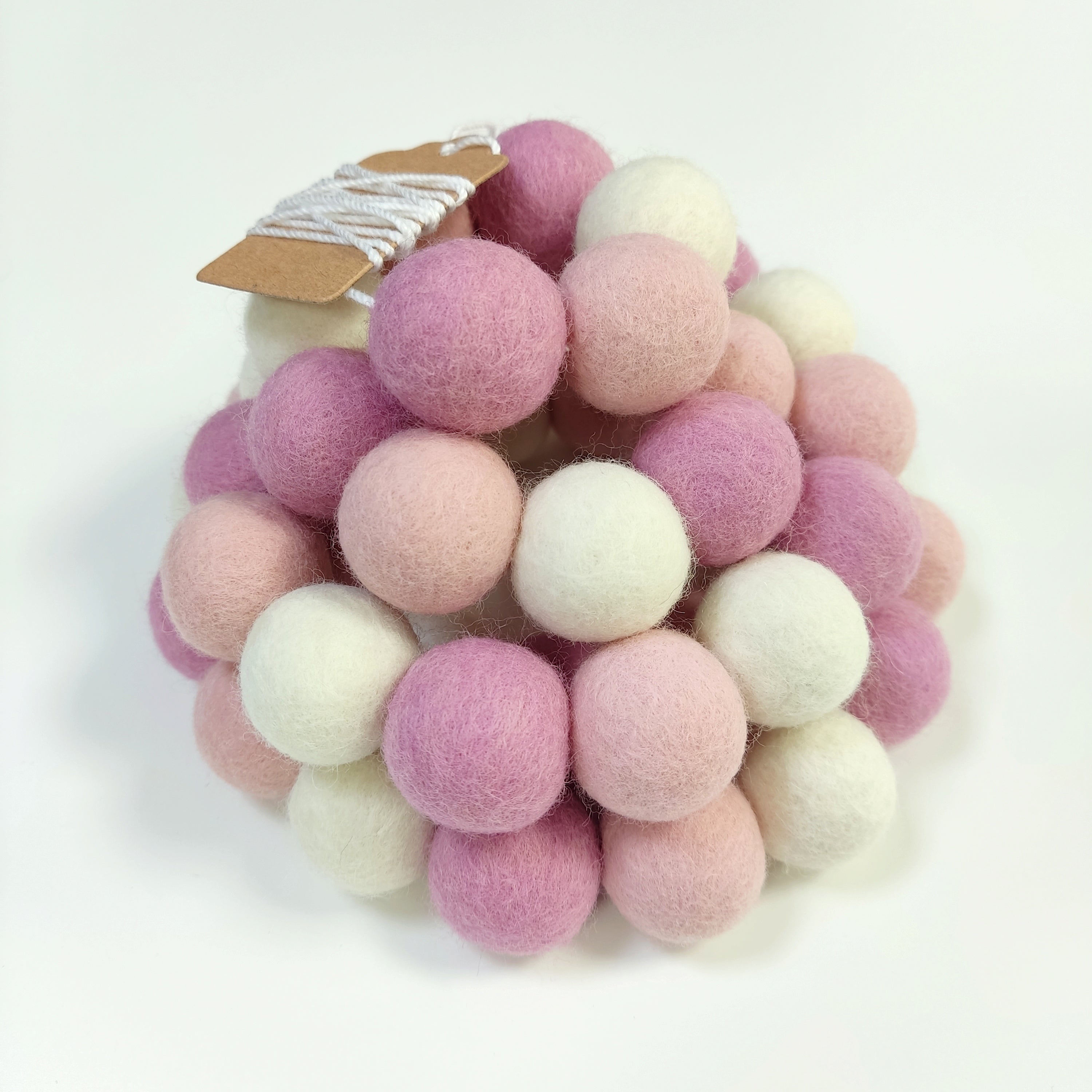 Zoom sur la guirlande de pompons feutrés guimauve rose avec étiquette