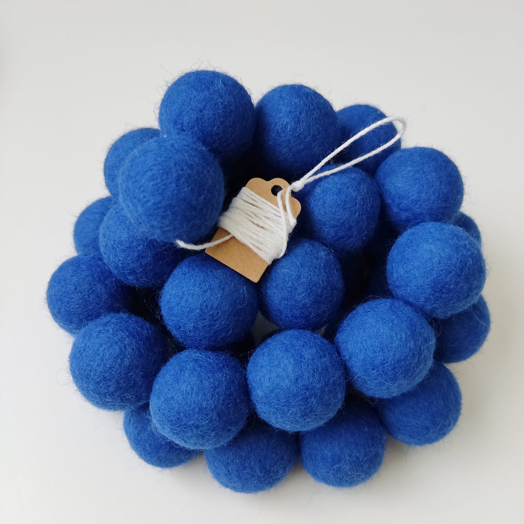 Zoom sur la guirlande en boules de feutre indigo avec étiquette