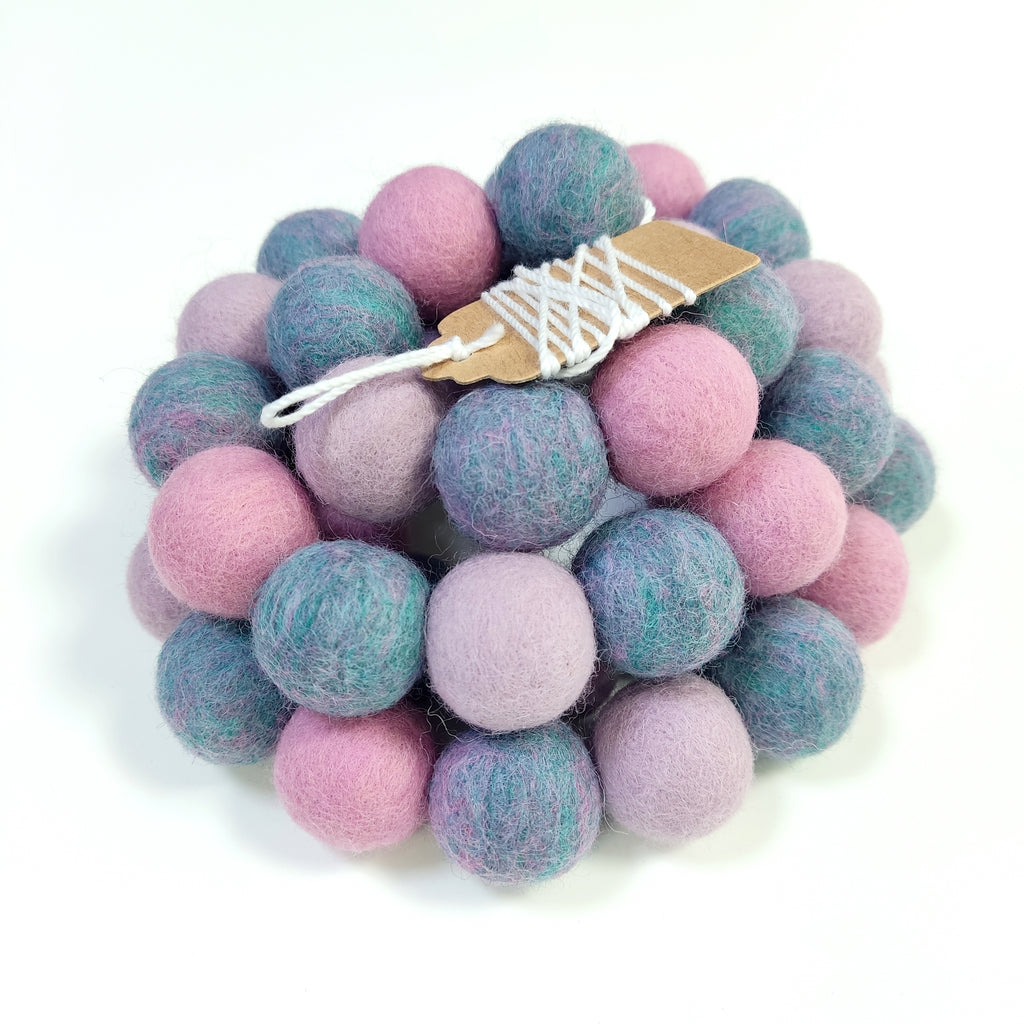 Zoom sur la guirlande de pompons en laine mérinos jardin de lilas avec étiquette CELAINEDECO