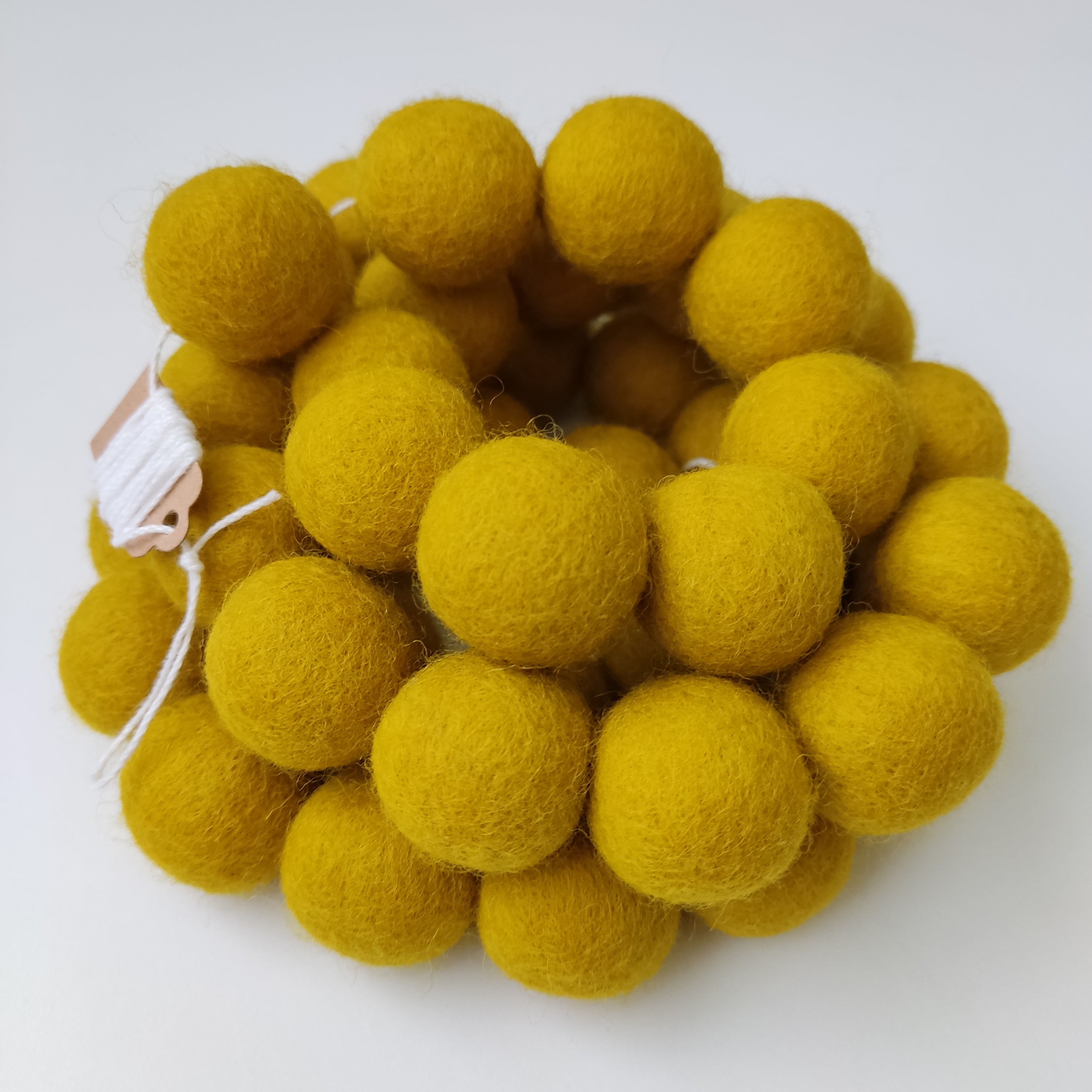Guirlande en boules de feutre jaune moutarde de près avec étiquette