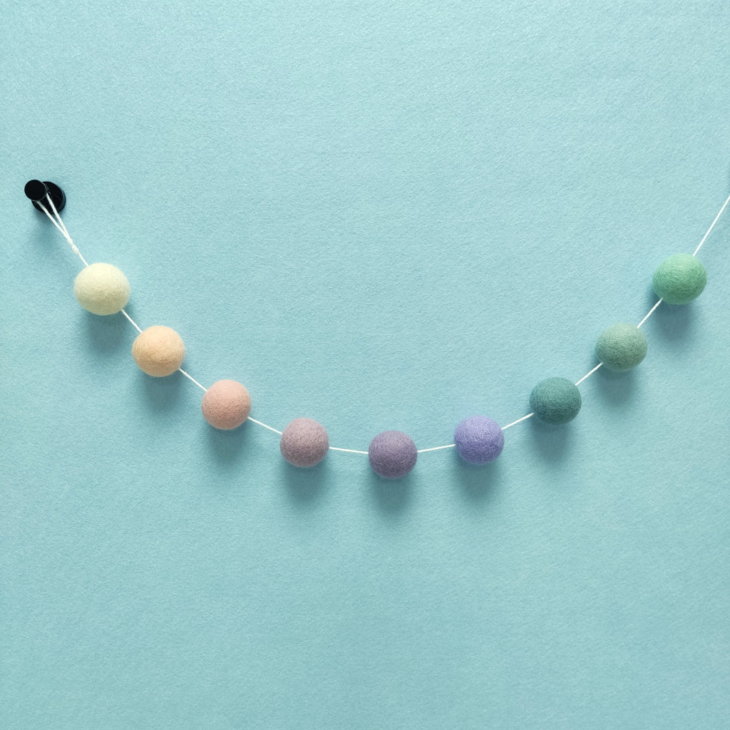 Détail des pompons feutrés blanc crème, beige rosé, rose poudré, lilas, mauve, lavande, bleu nordique, vert céladon et vert menthe