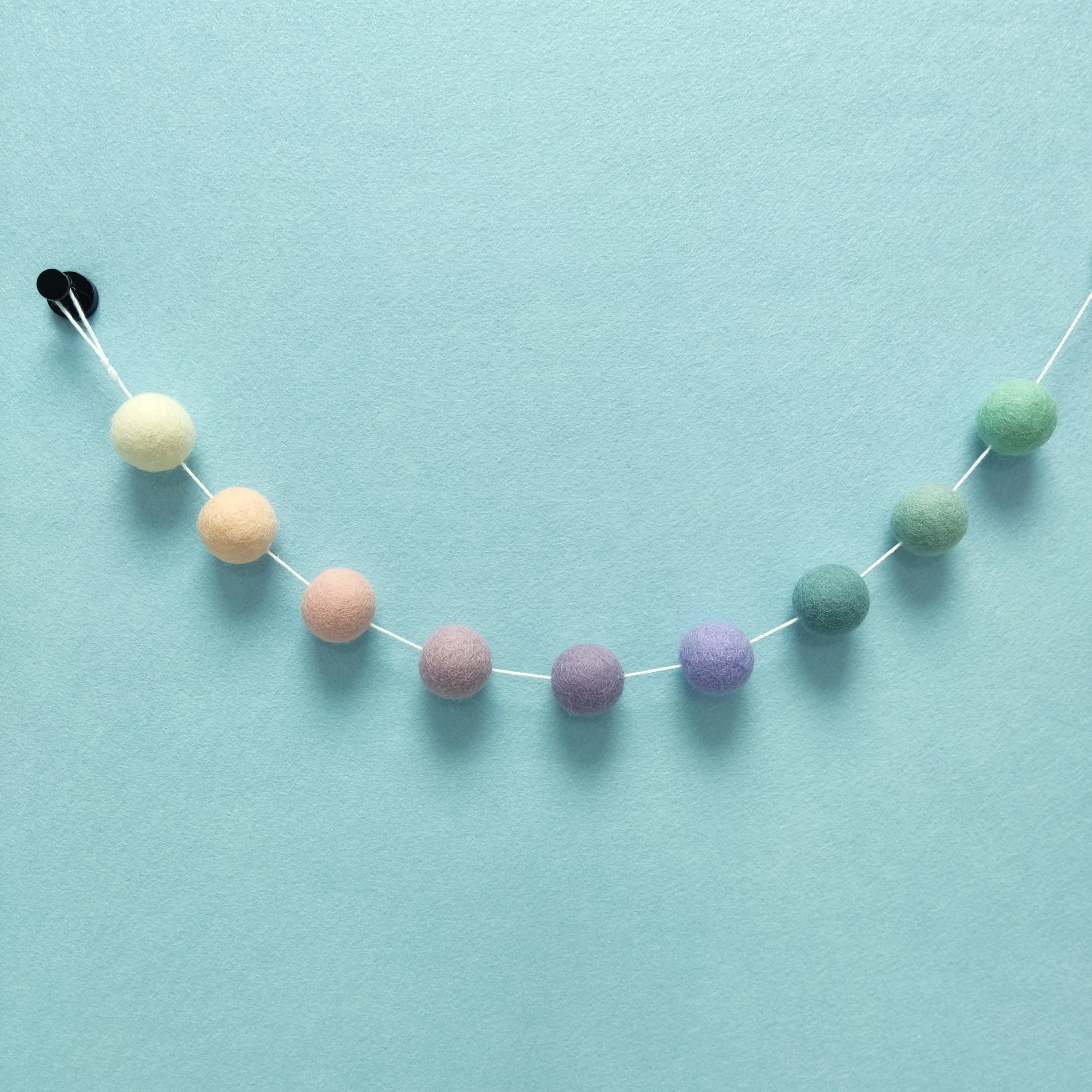 Détail des pompons feutrés blanc crème, beige rosé, rose poudré, lilas, mauve, lavande, bleu nordique, vert céladon et vert menthe