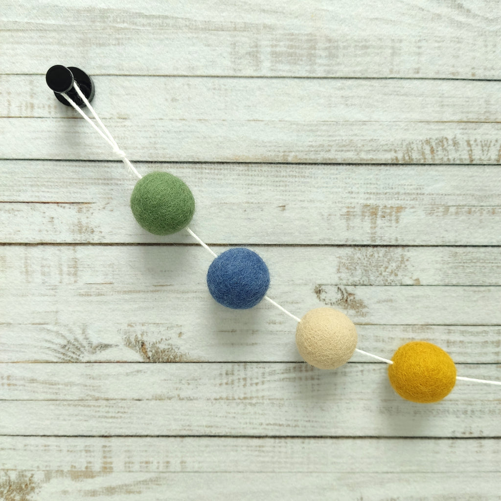 Détails des 4 couleurs de pompons en feutre ocre doré, beige poudré, bleu denim et vert matcha