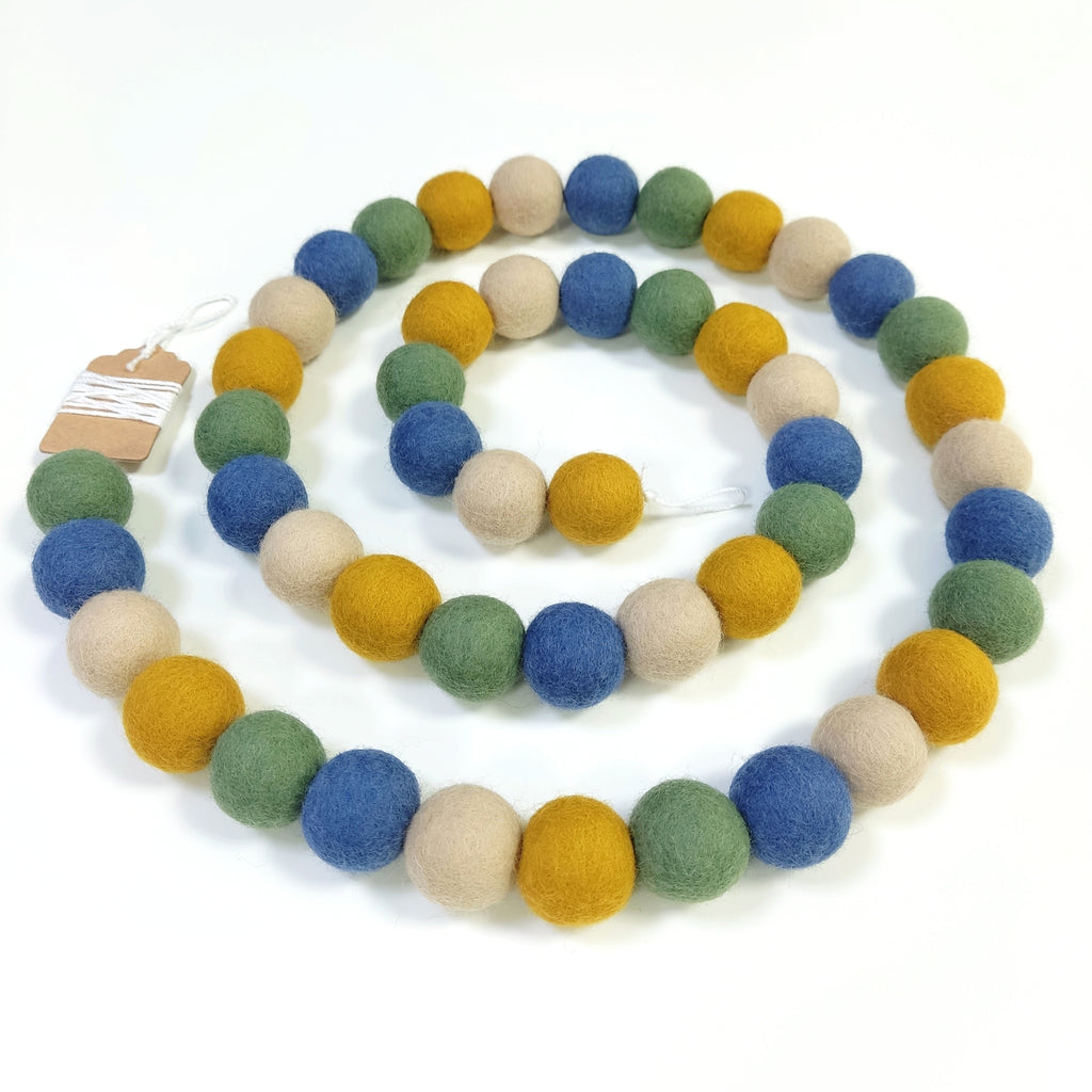 Guirlande de pompons de feutre matcha ocre posée en forme de spirale vue de dessus