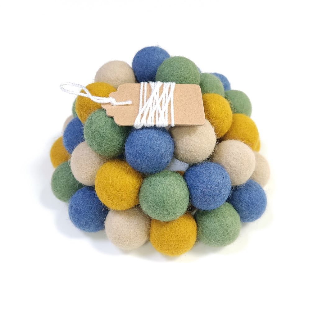 Zoom sur la guirlande en boules de feutre bleu vert ocre beige avec étiquette