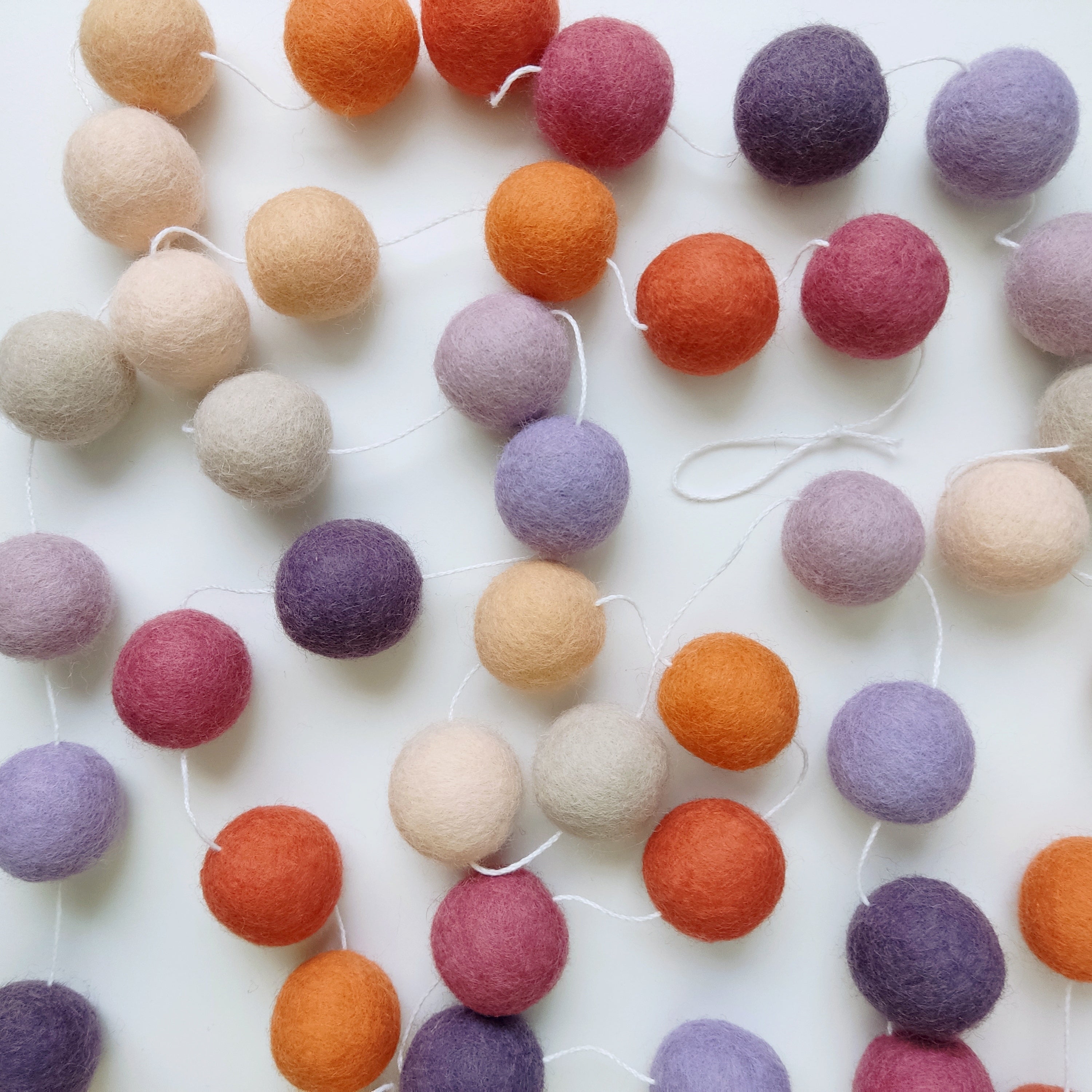 Pompons feutrés de la guirlande mauve orange étalés sur une table