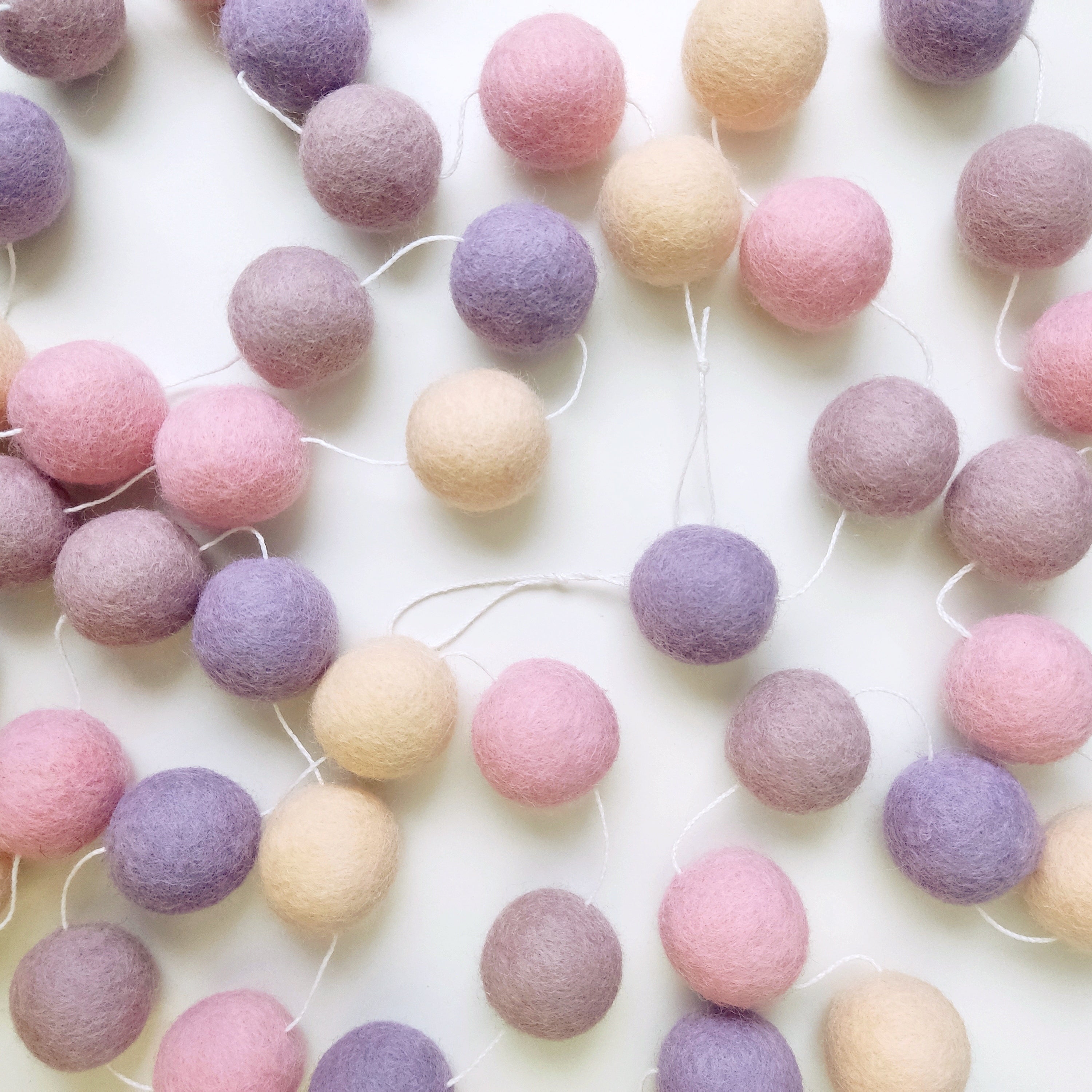 Guirlande de pompons en laine feutrée étalée sur une table