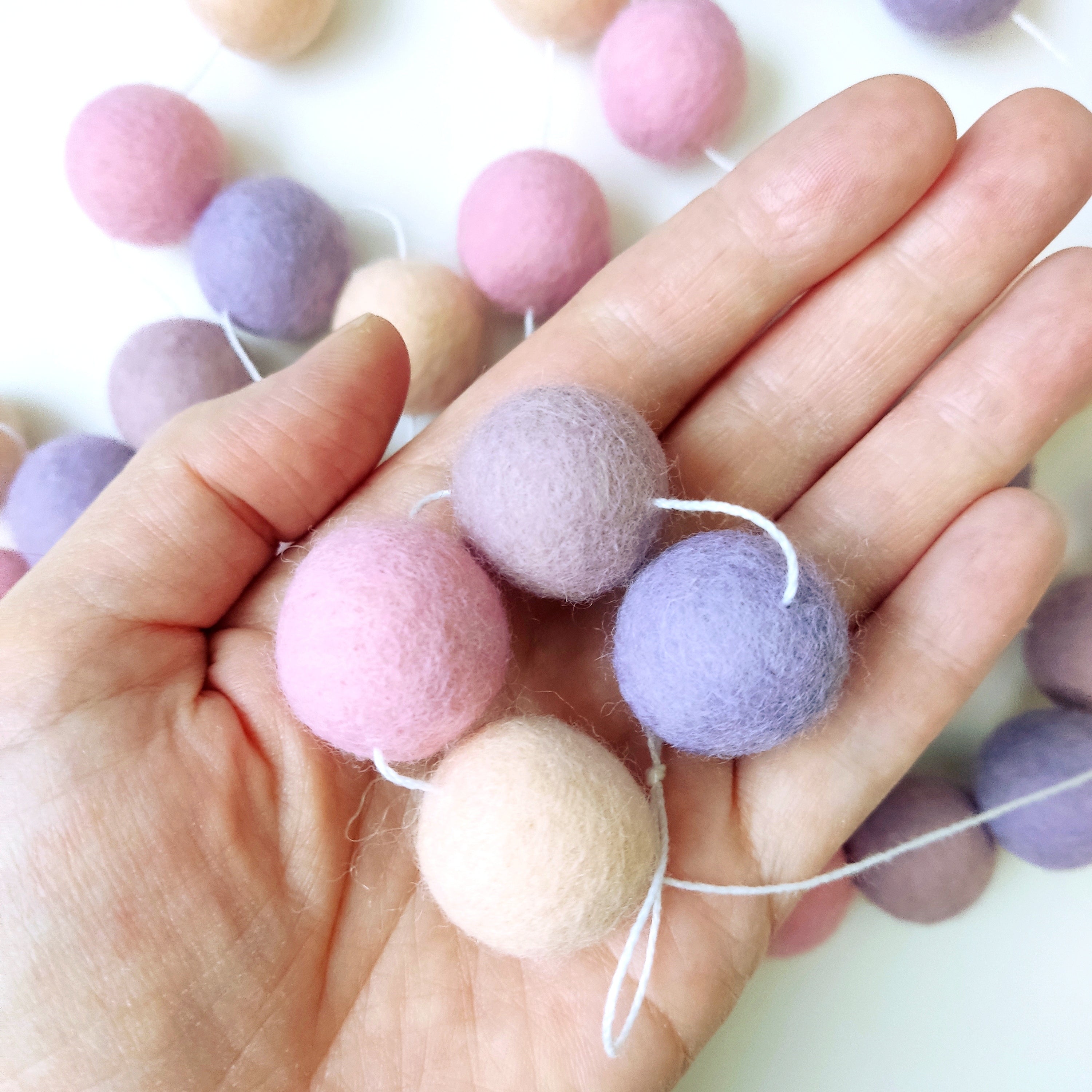 Détails des pompons de 2,5 cm de la guirlande mauve rose dans une main