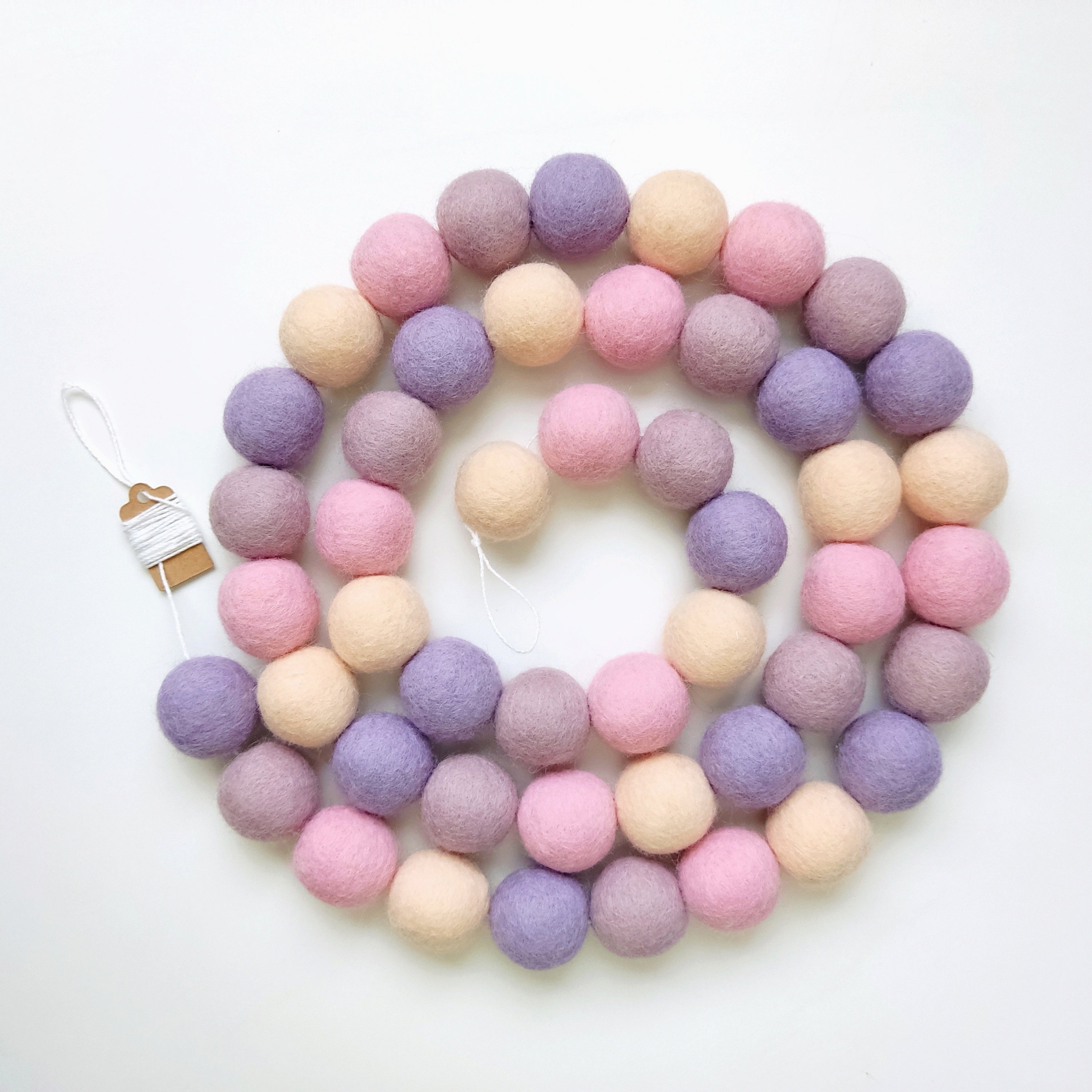 Guirlande de pompons mauve rose disposée en spirale, vue de dessus