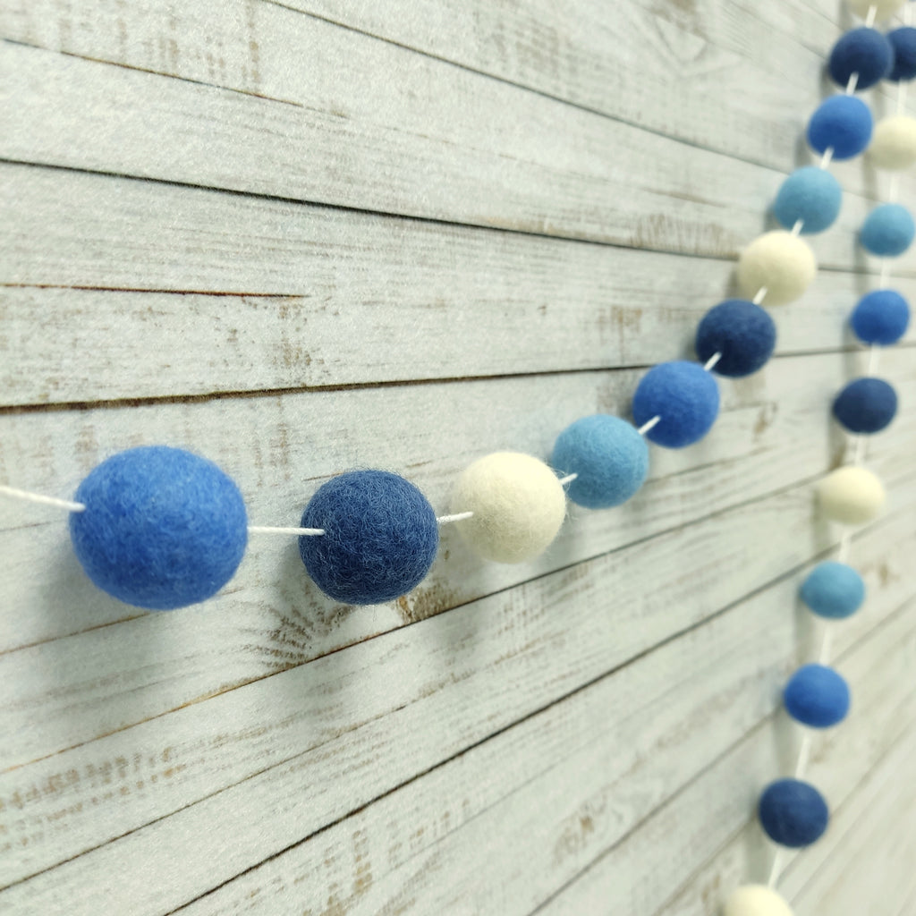 Guirlande de pompons bleu ciel, bleu lavande, bleu denim et blanc vue de profil