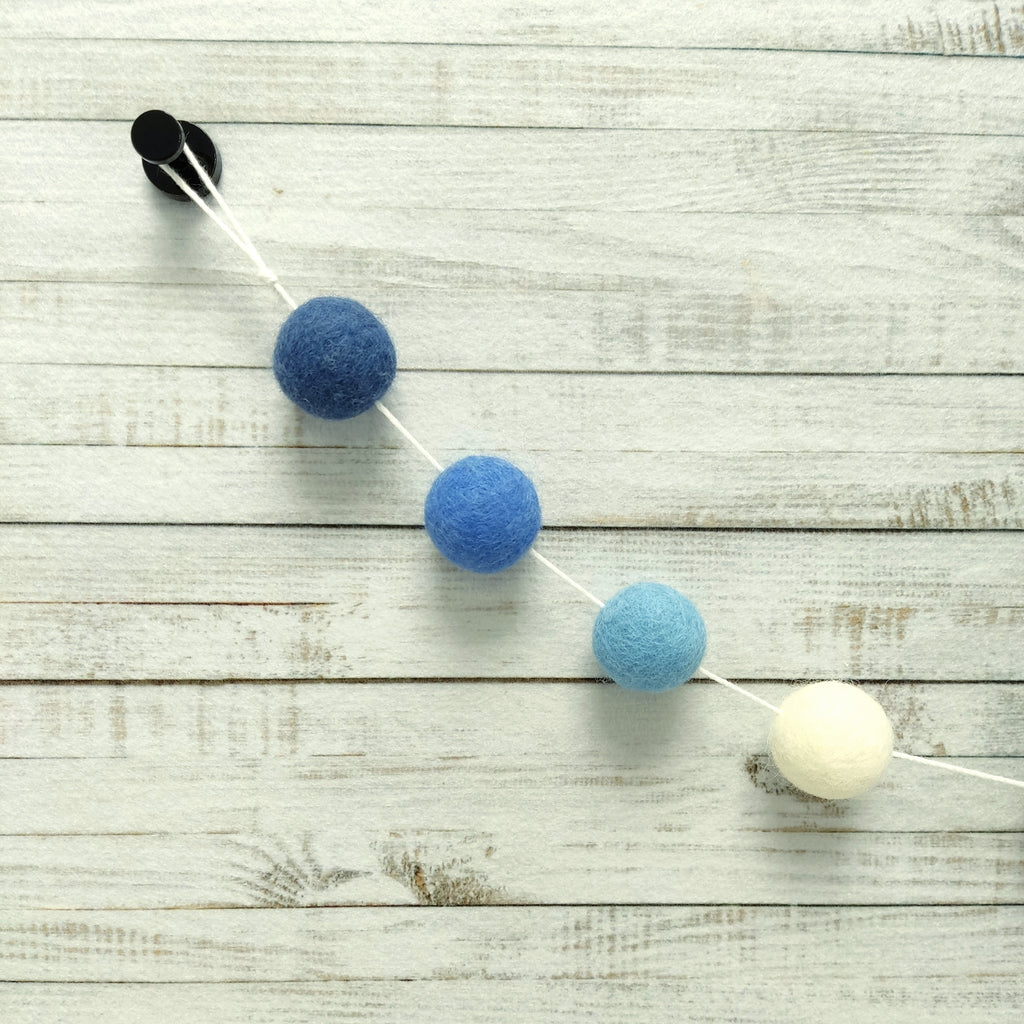 Zoom sur les pompons feutrés de laine mérinos de 2,5 cm bleu et blanc de la guirlande méditerranée