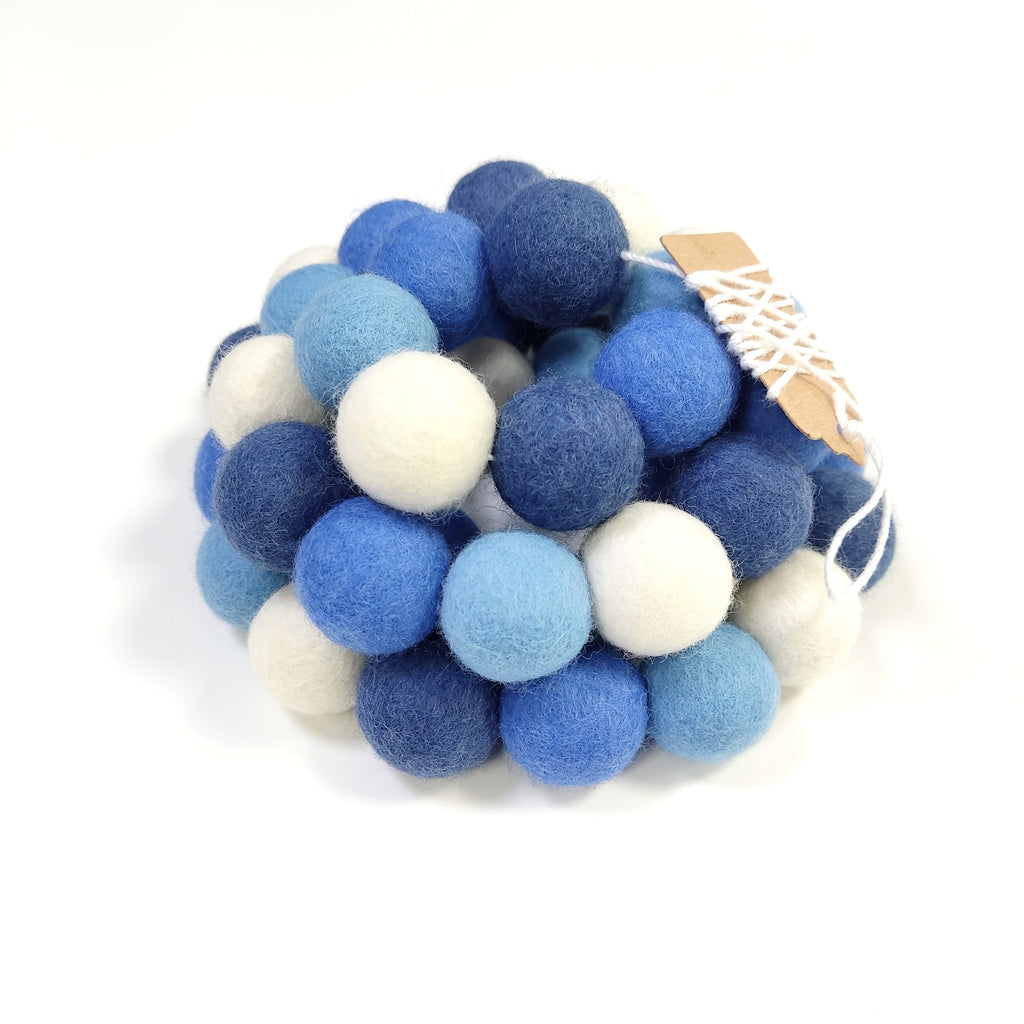 Zoom sur la guirlande de pompons décorative bleu et blanc avec étiquettes