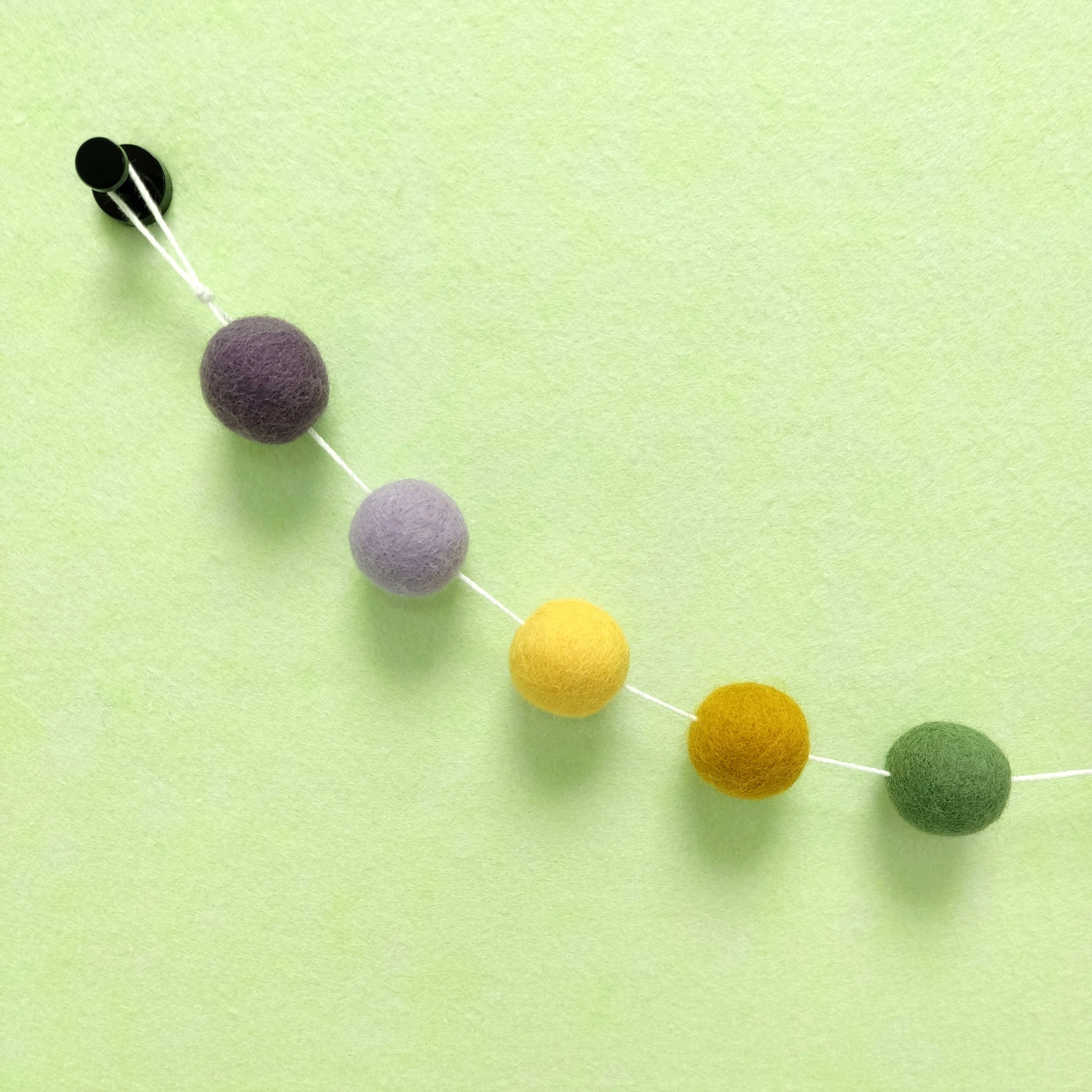 Détail des 5 couleurs de pompons feutrés jaune maïs, ocre doré , vert matcha, mauve et violet améthyste
