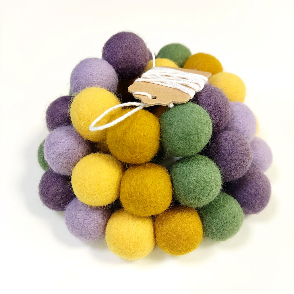 Zoom sur la guirlande de pompons en laine mérinos miel lavande avec étiquette CELAINEDECO